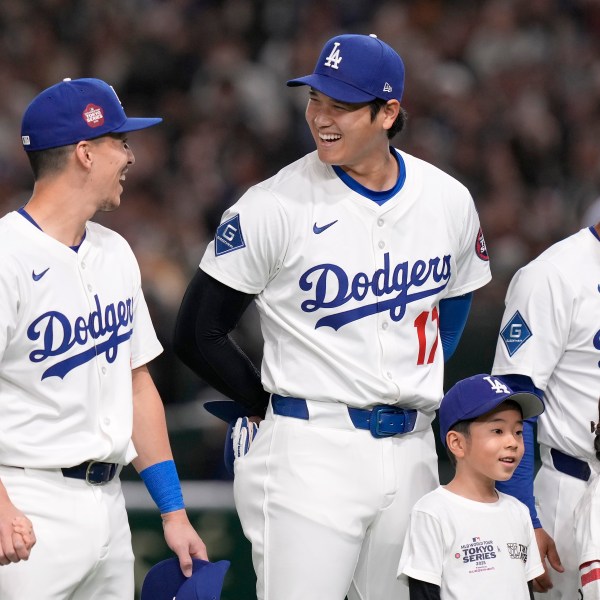 Los Angeles Dodgers' Tommy Edman, Shohei Ohtani and manager Dave Roberts stand on the field