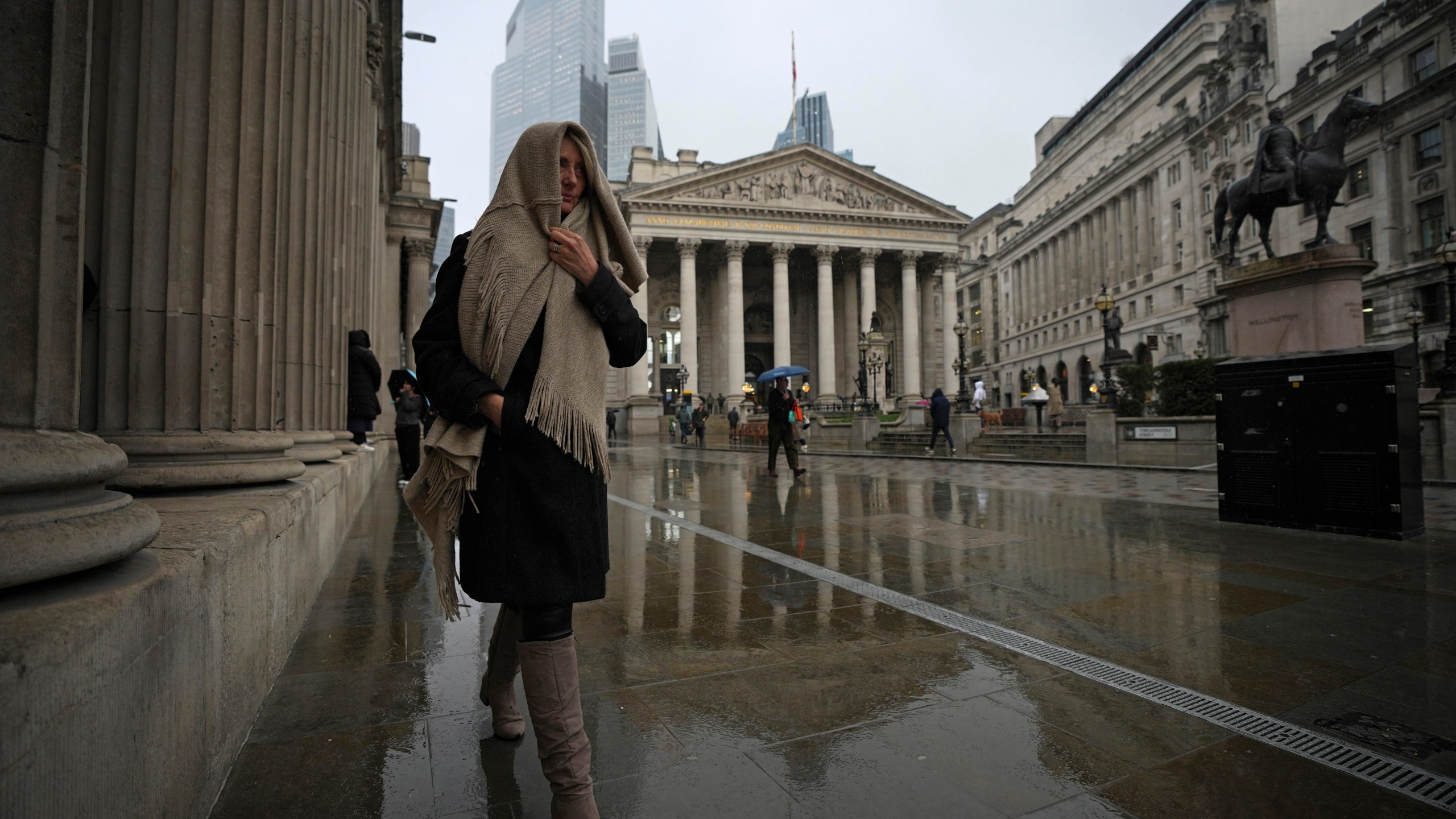 A woman walks past the Bank of England, at the financial district, in London, Thursday, March 13, 2025. (AP Photo/Kin Cheung)