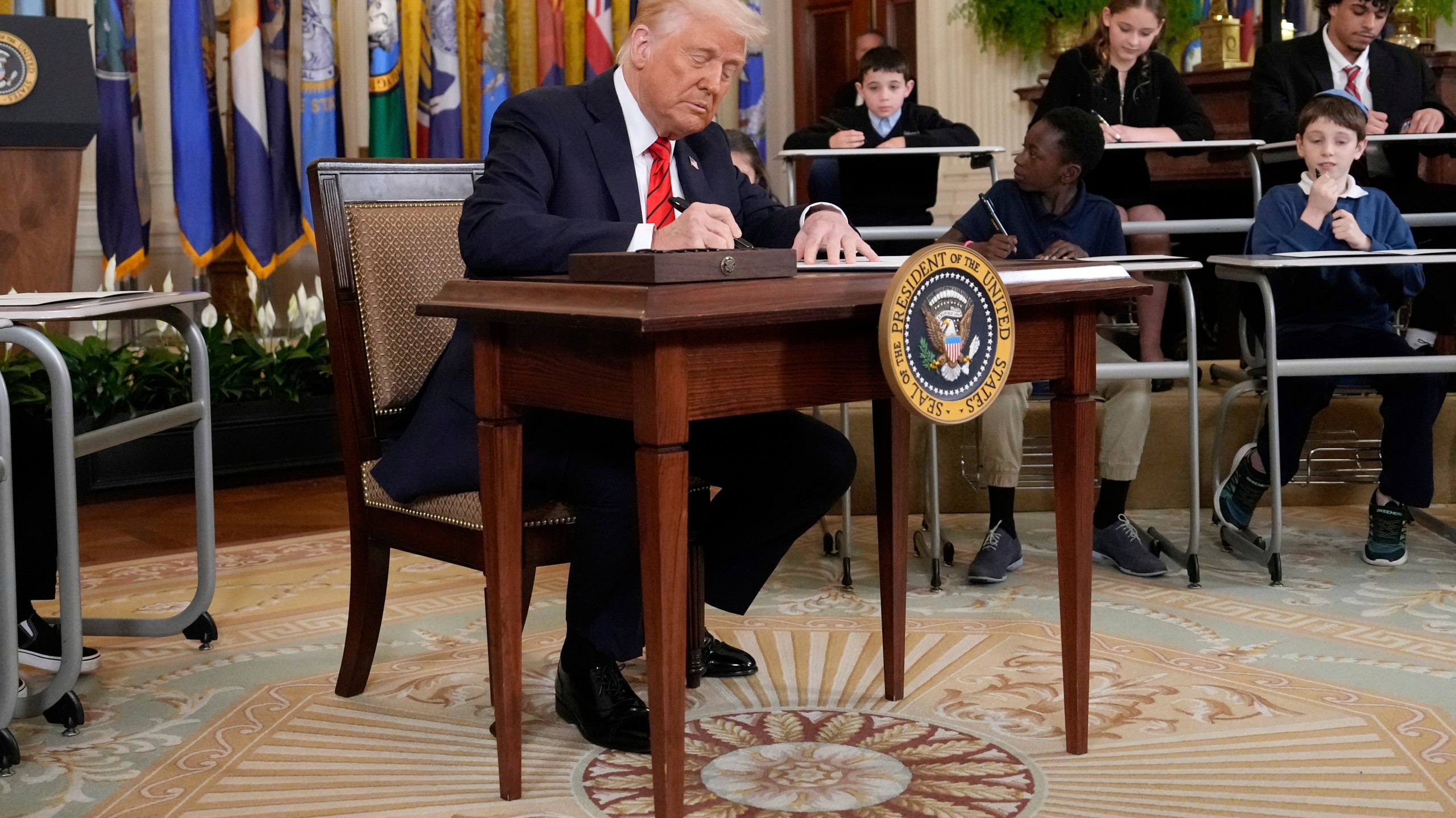 President Donald Trump signs an executive order in the East Room of the White House in Washington, Thursday, March 20, 2025. (AP Photo/Ben Curtis)