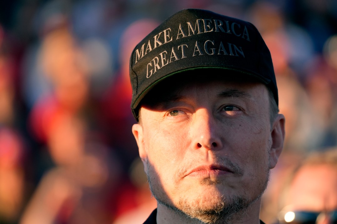 Elon Musk wearing a MAKE AMERICA GREAT AGAIN hat at a campaign event