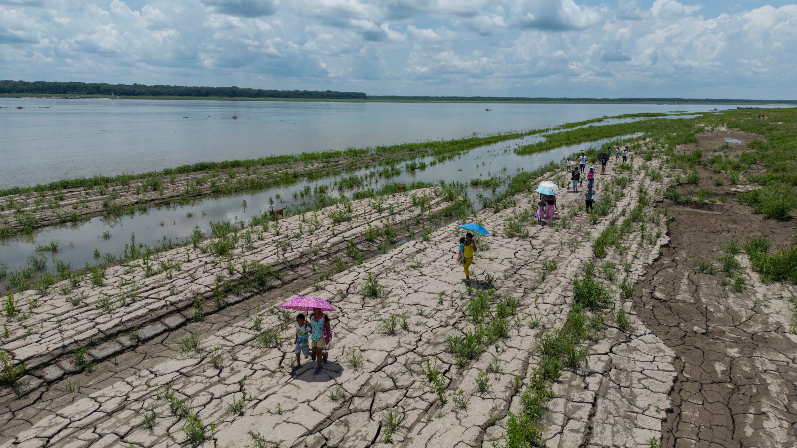FILE - People walk through a part of the Amazon River that shows signs of drought, in Santa Sofia, on the outskirts of Leticia, Colombia, Oct. 20, 2024. (AP Photo/Ivan Valencia, File)