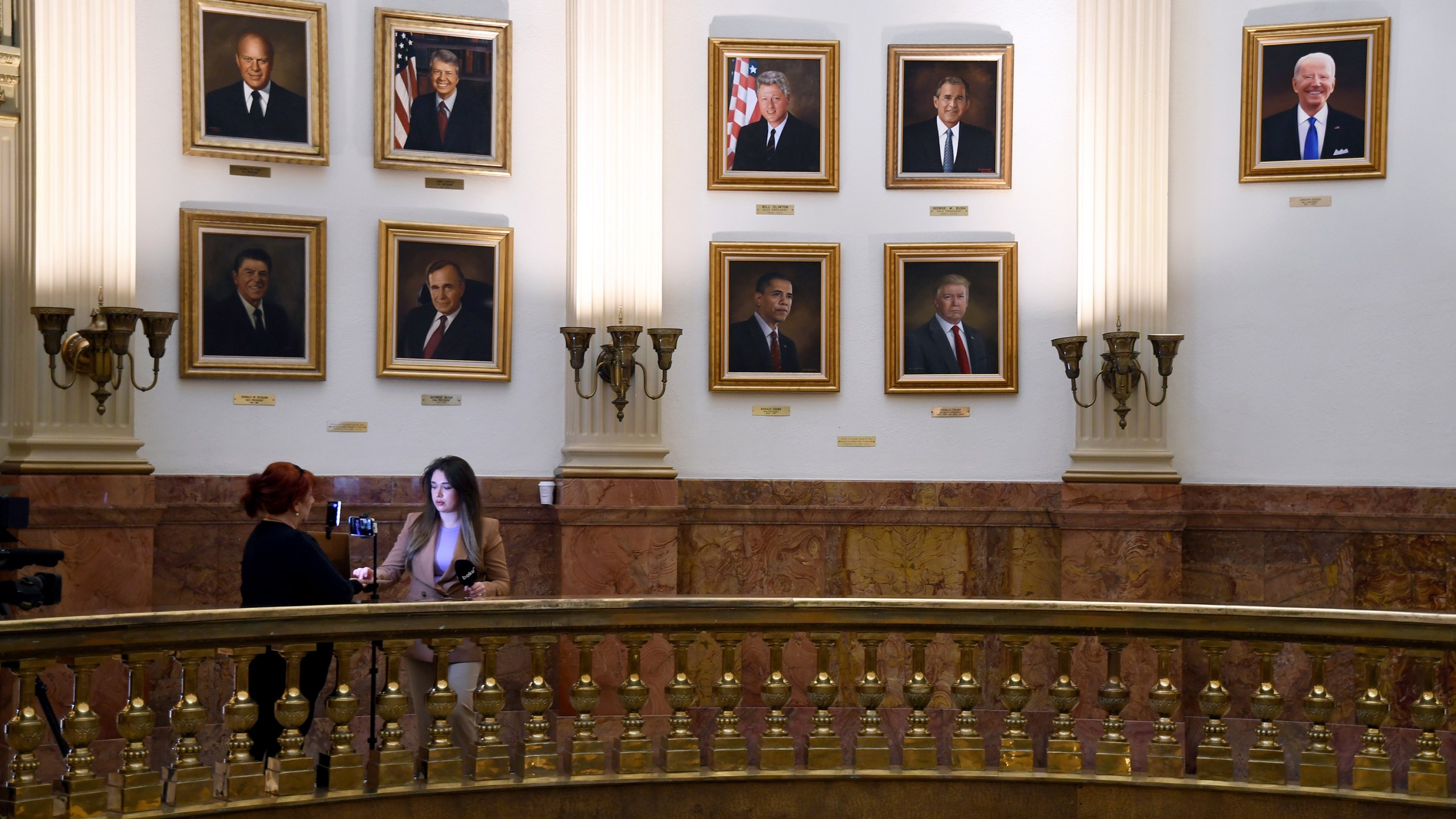 A news crew works in front of a wall of presidential portraits at the Colorado Capitol on Monday, March 24, 2025, in Denver. (AP Photo/Thomas Peipert)