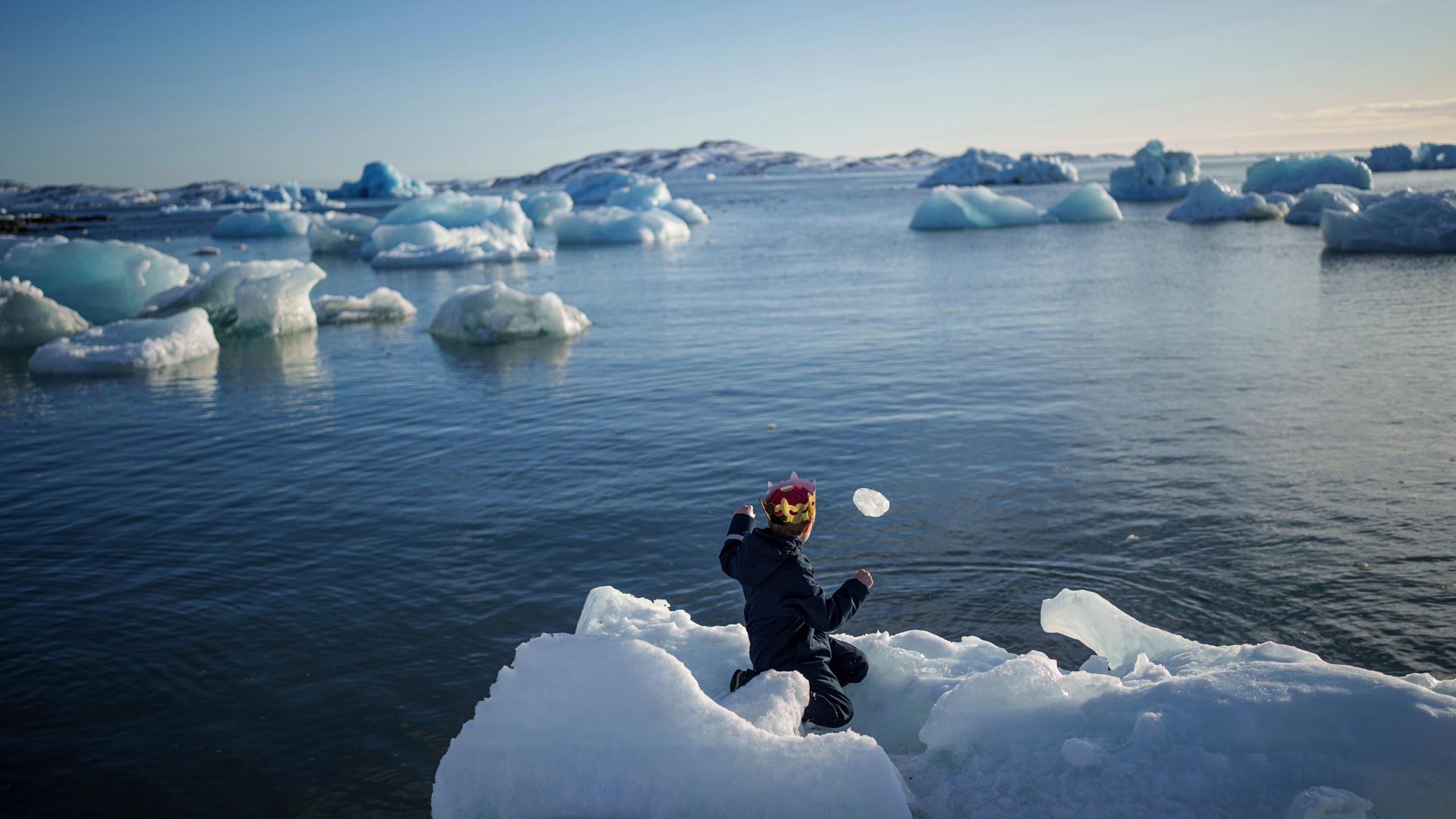 A boy throws ice into the sea in Nuuk, Greenland, Tuesday, March 11, 2025. (AP Photo/Evgeniy Maloletka)
