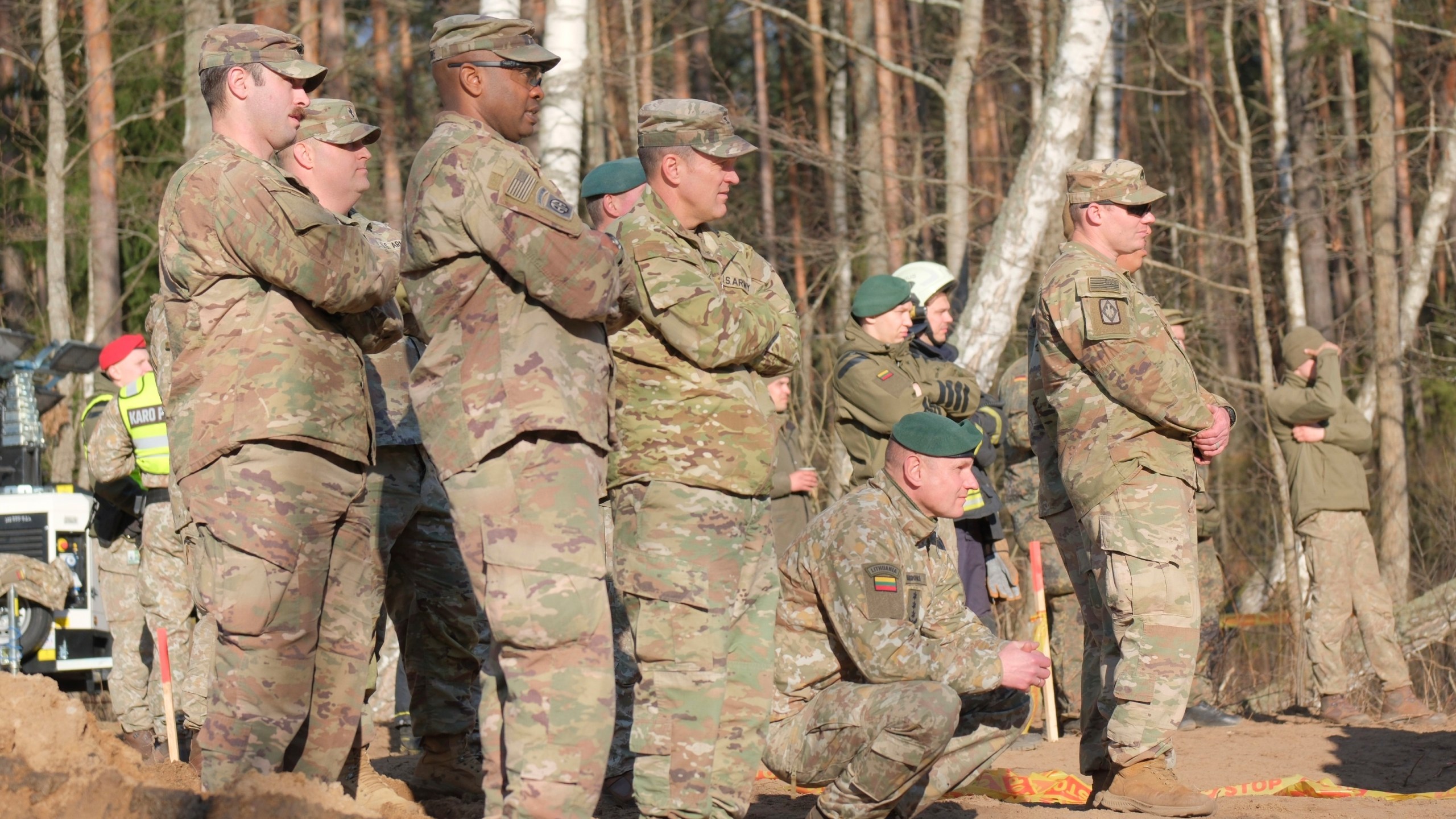 In this image provided by the U.S. Army, U.S. Army soldiers from the 1st Armored Brigade Combat Team, 3rd Infantry Division, along with Lithuanian Army and emergency services personnel, watch as an excavator builds a dam during recovery efforts for four U.S. soldiers in a U.S. Army M88 Hercules submerged under several meters of water and in a swamp near a training area near Pabadre, Lithuania, Thursday, March 27, 2025. (Christopher Saundersn/U.S. Army via AP)