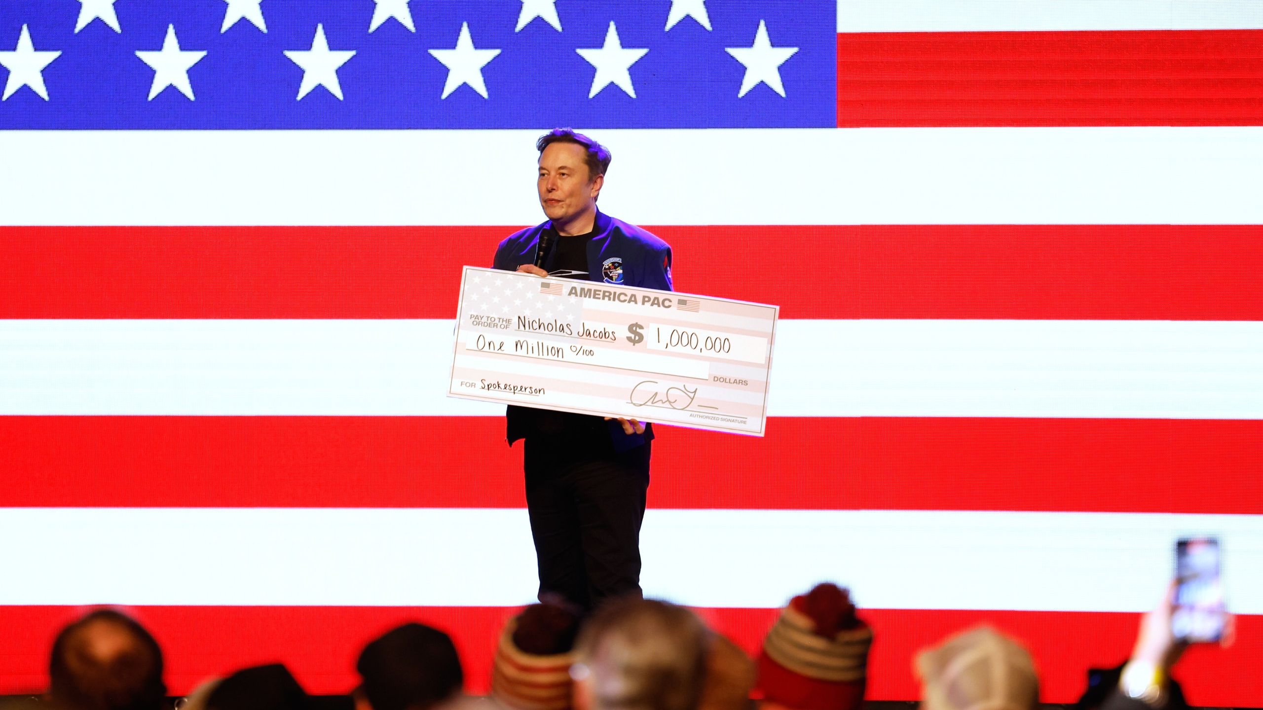 Elon Musk holds a check for $1 million dollars at a town hall Sunday, March 30, 2025, in Green Bay, Wis. (AP Photo/Jeffrey Phelps)