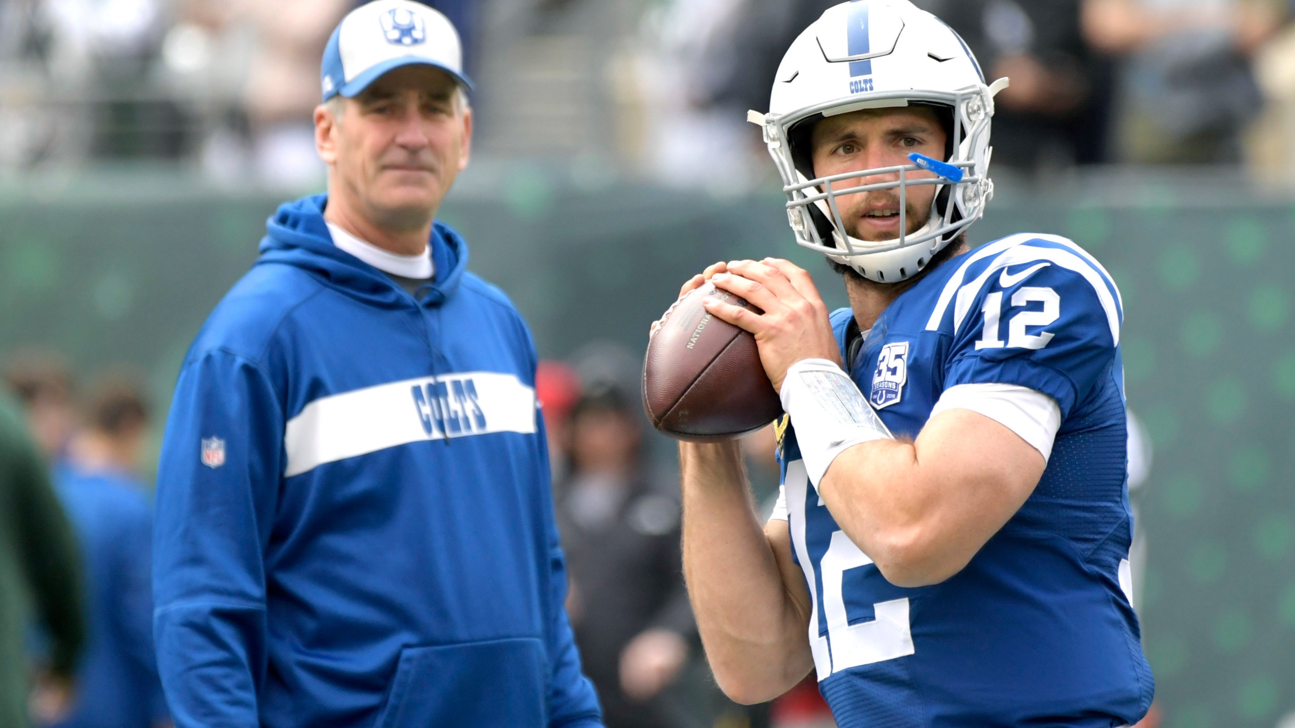 FILE - Indianapolis Colts quarterback Andrew Luck (12) warms up as head coach Frank Reich looks on prior to an NFL football game against the New York Jets, in East Rutherford, N.J, Oct. 14, 2018. (AP Photo/Bill Kostroun, File)