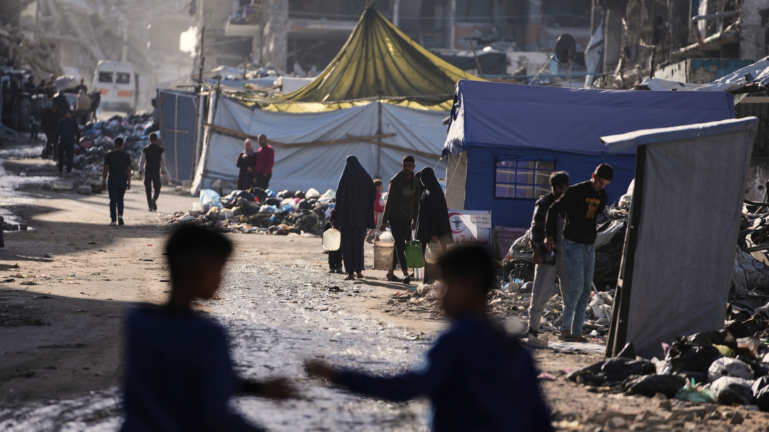 Displaced Palestinians carry water next to destructions in Jabaliya, Gaza Strip on Monday, March 31, 2025. (AP Photo/Jehad Alshrafi)