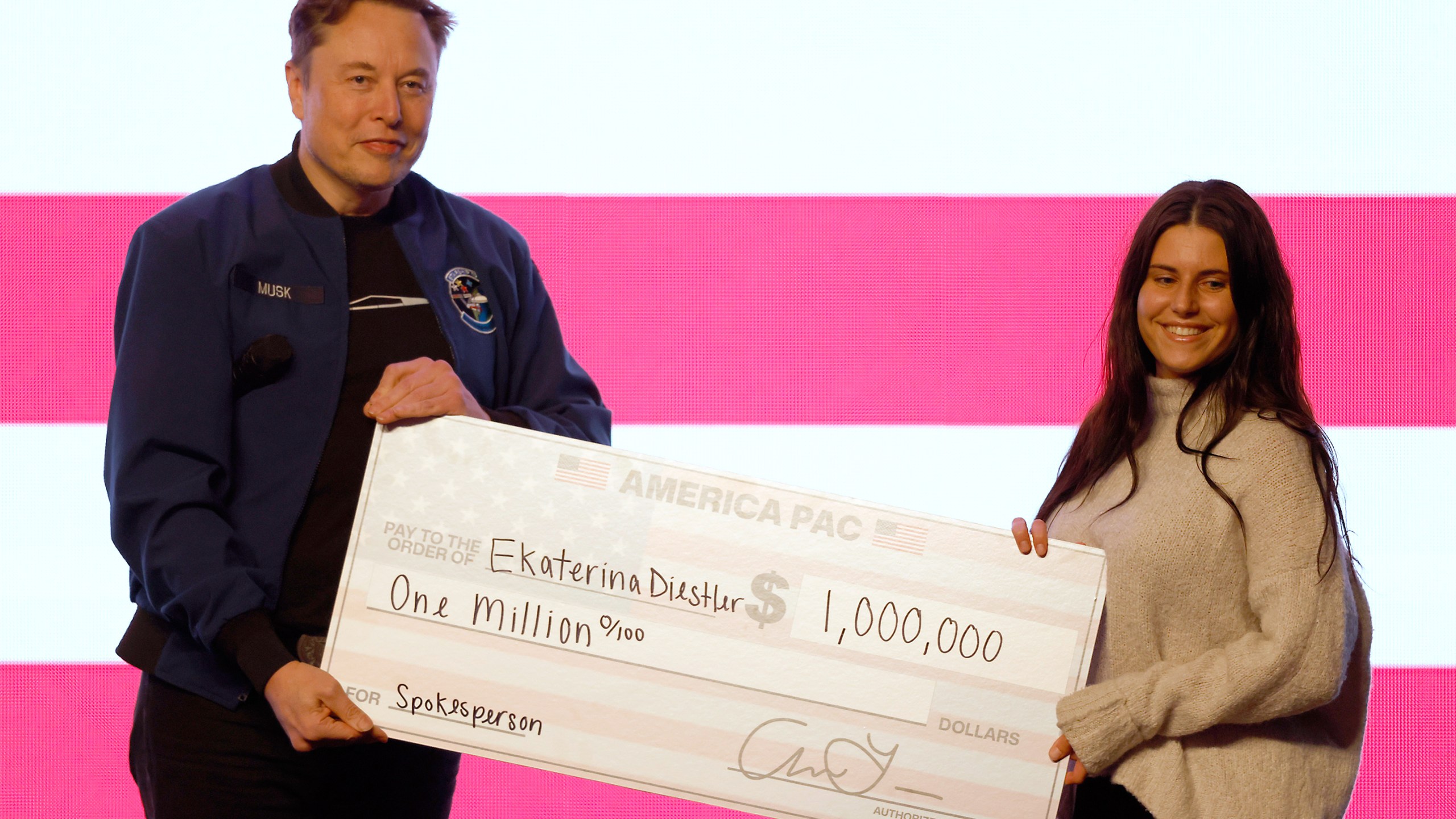 Elon Musk presents a check for $1 million dollars during a town hall Sunday, March 30, 2025, in Green Bay, Wis. (AP Photo/Jeffrey Phelps)