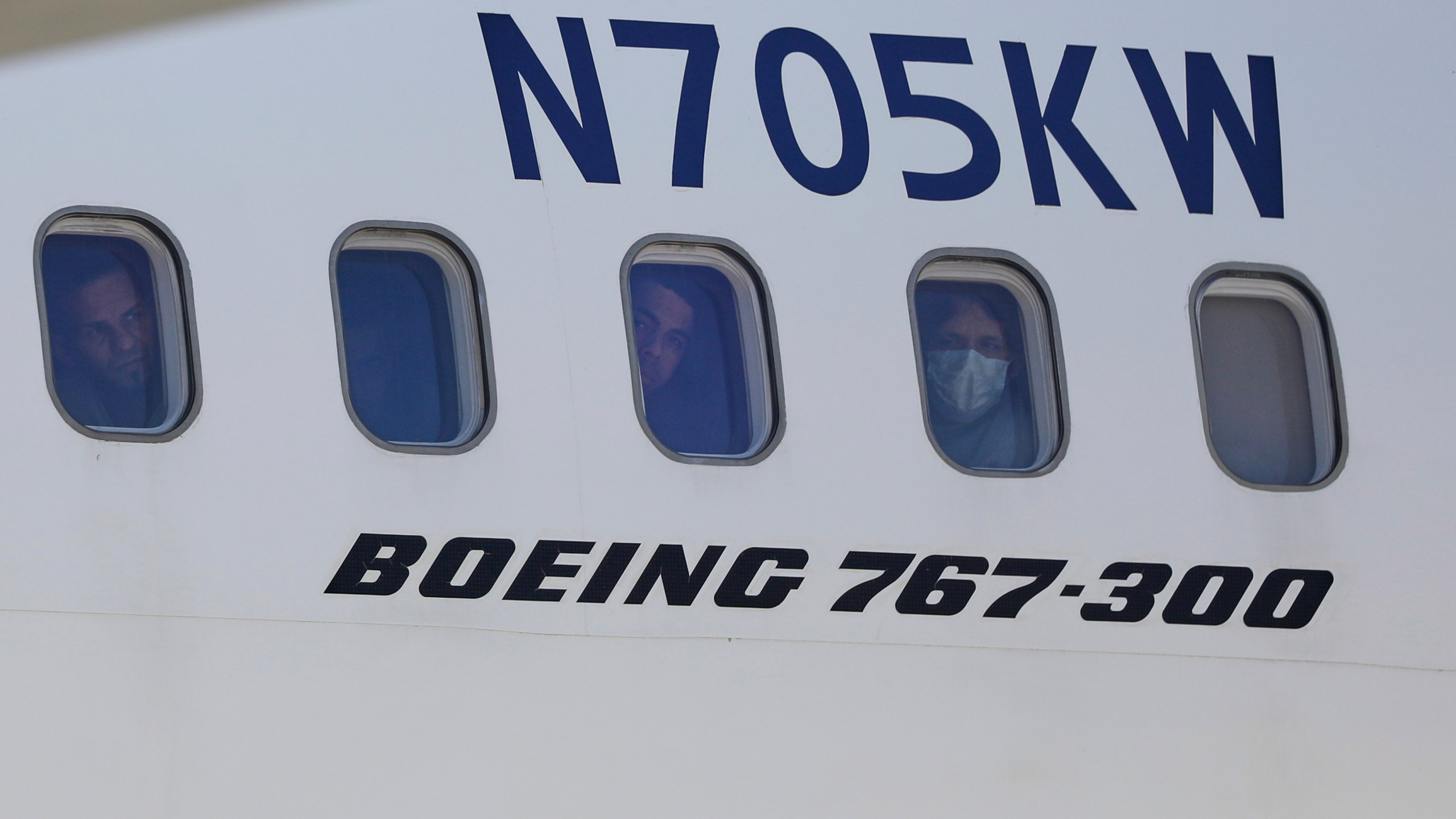 Venezuelan migrants deported from the United States peer through windows of an Eastern Airlines plane upon arriving at Simon Bolivar International Airport in Maiquetia, Venezuela, Sunday, March 30, 2025. (AP Photo/Cristian Hernandez)