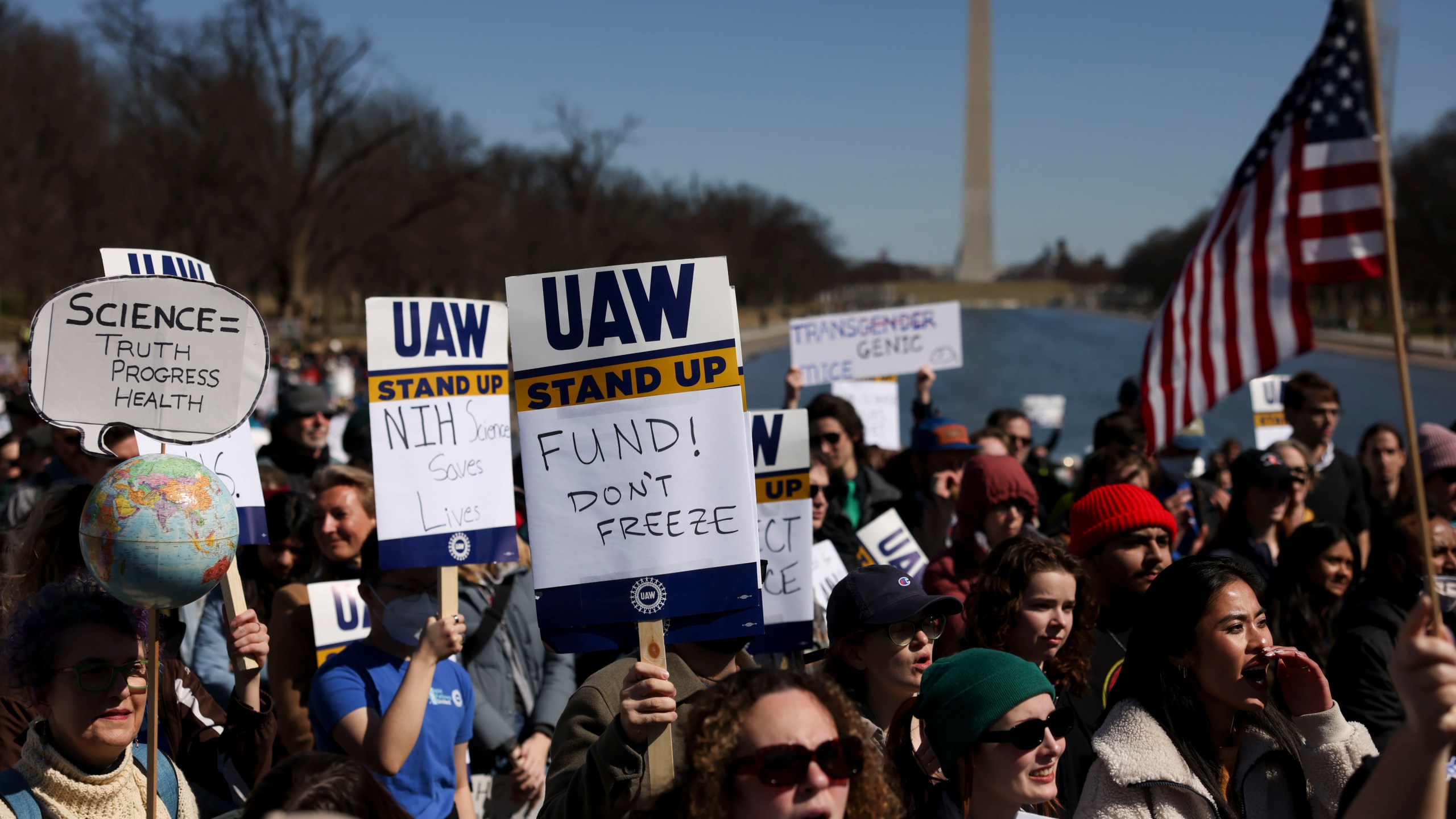 Demonstrators hold signs during a "Stand Up For Science" rally at the Lincoln Memorial in Washington, DC, US, on Friday, March 7, 2025. A federal judge issued a nationwide block against the Trump administration's moves to slash funds from the National Institutes of Health that cover grant recipients research overhead costs, dealing a blow to one of the government's efforts to reduce spending. Photographer: Tierney L. Cross/Bloomberg via Getty Images