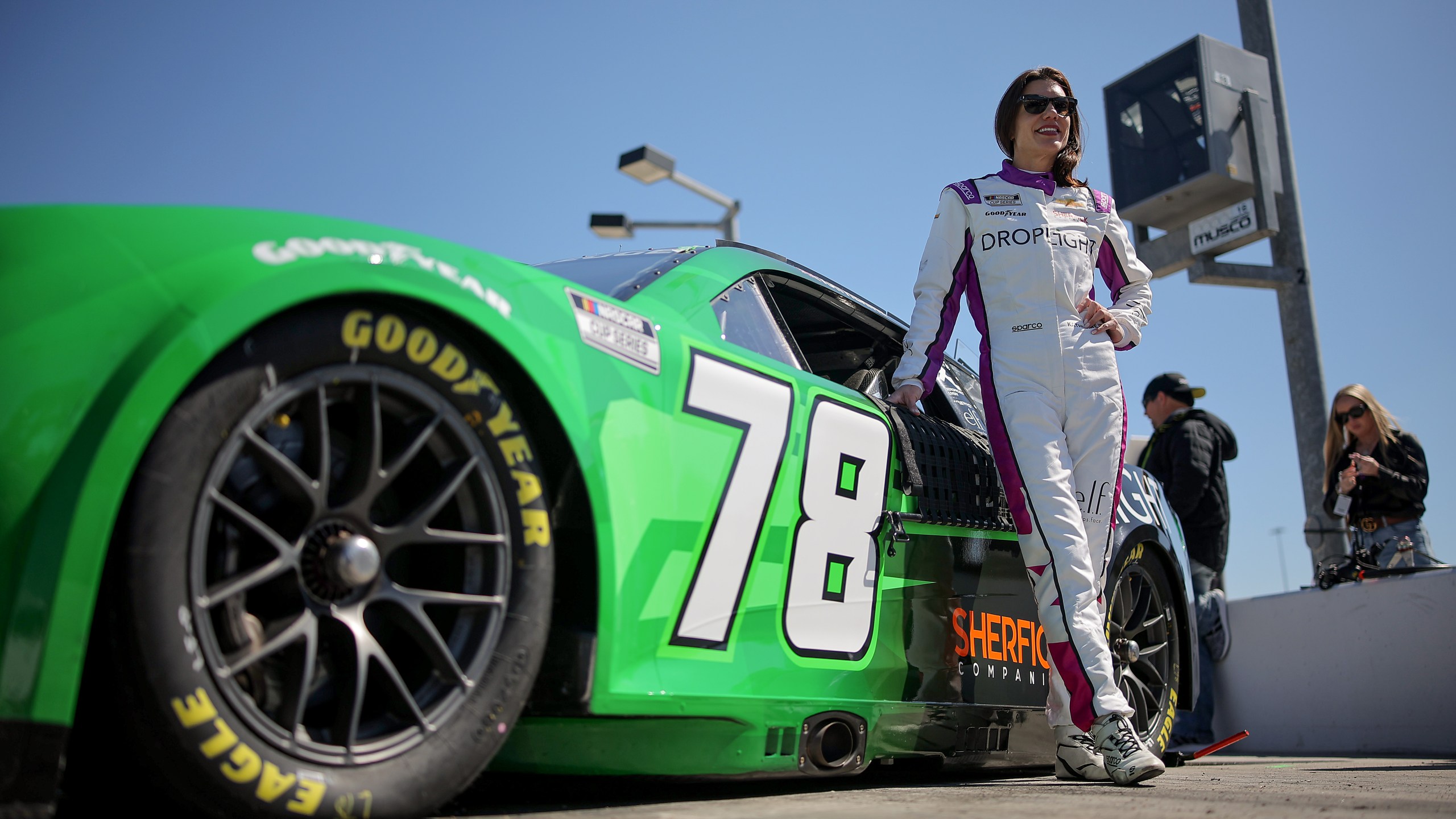 Katherine Legge stands next to a racecar