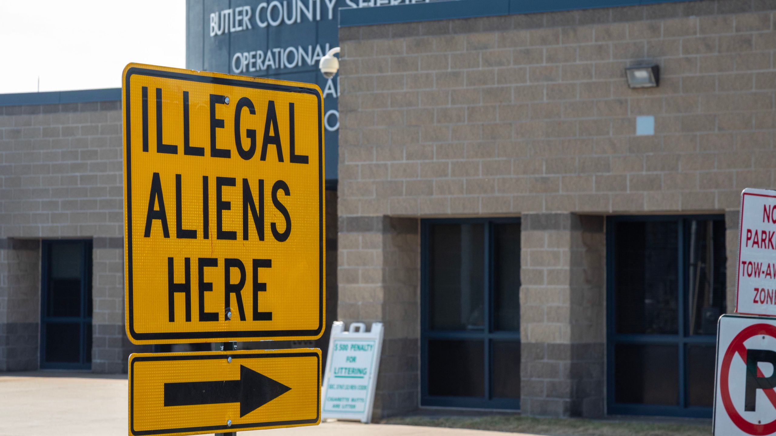 Sign saying "Illegal Aliens Here" with arrow outside jail