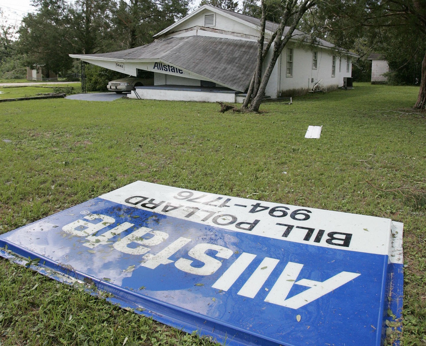 Flattened house with insurance sign in foreground