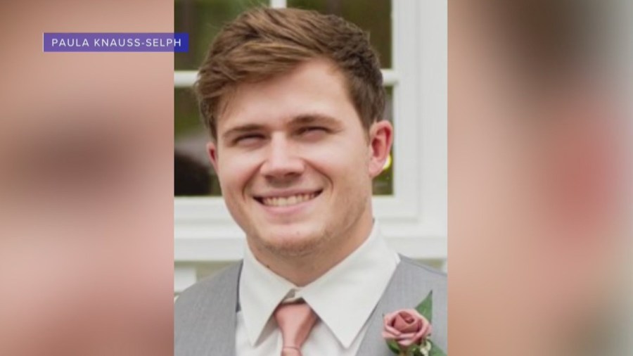 Ryan Knauss smiles in a photo while wearing a suit