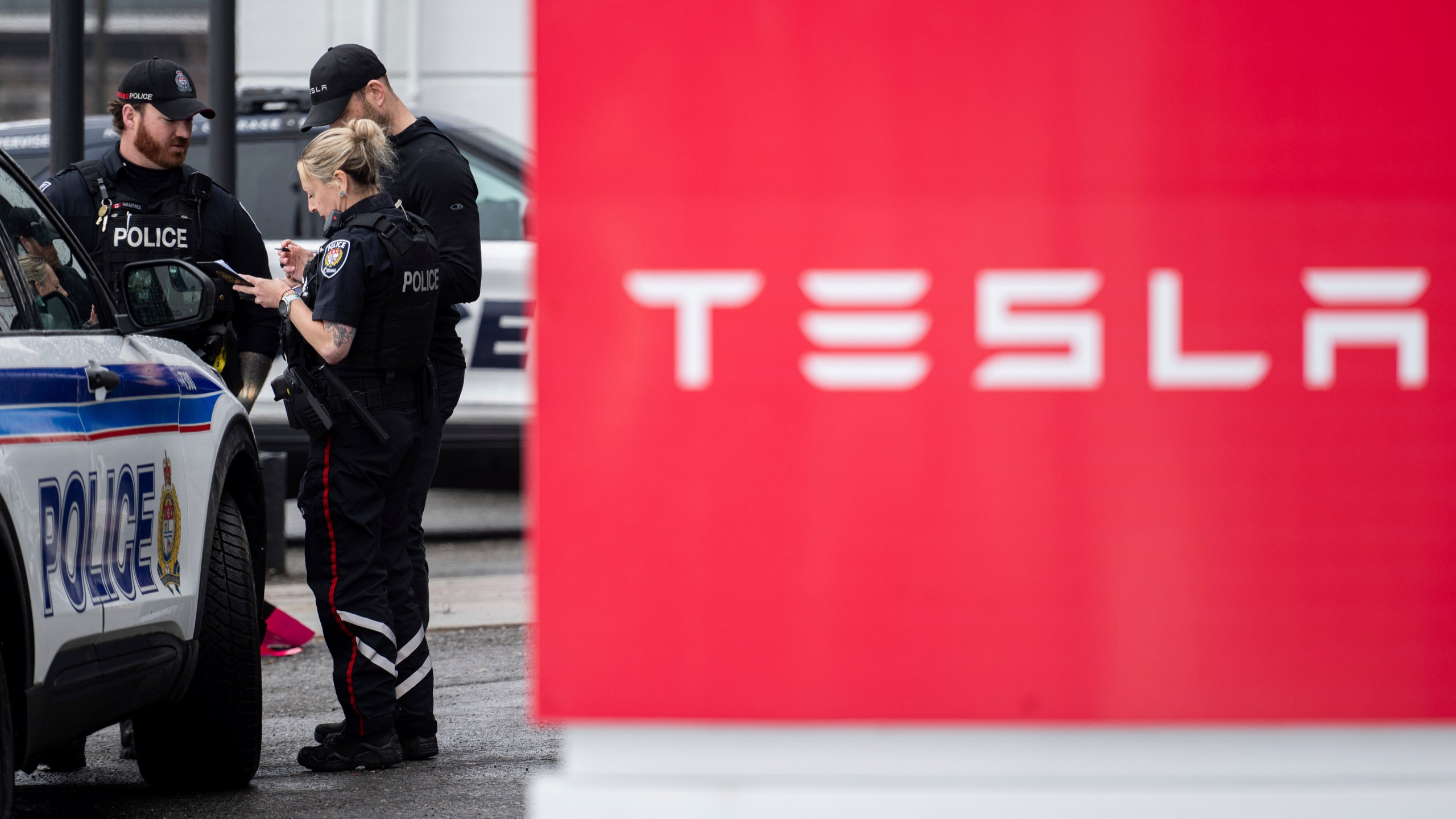 Officers from Ottawa Police Service (OPS) are seen at a Tesla Service and Showroom centre after it was damaged with pink spray paint in Ottawa, on Monday, March 31, 2025. (Spencer Colby/The Canadian Press via AP)