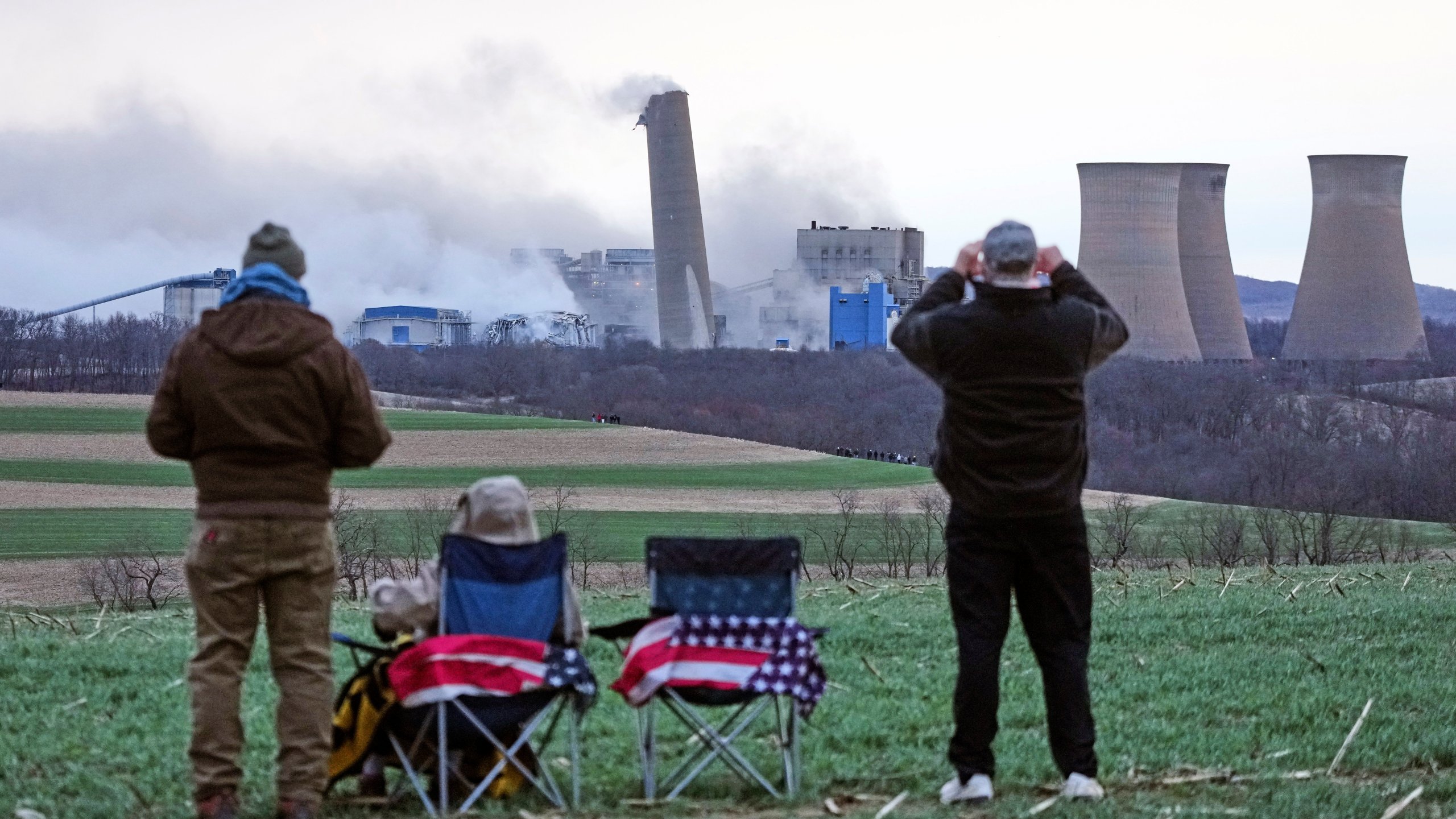 The smokestacks of the former coal-fired Homer City Generating Station crumble in a planned demolition to make way for a new natural gas-fired power plant in Homer City, Pa., Saturday, March 22, 2025. (AP Photo/Gene J. Puskar)