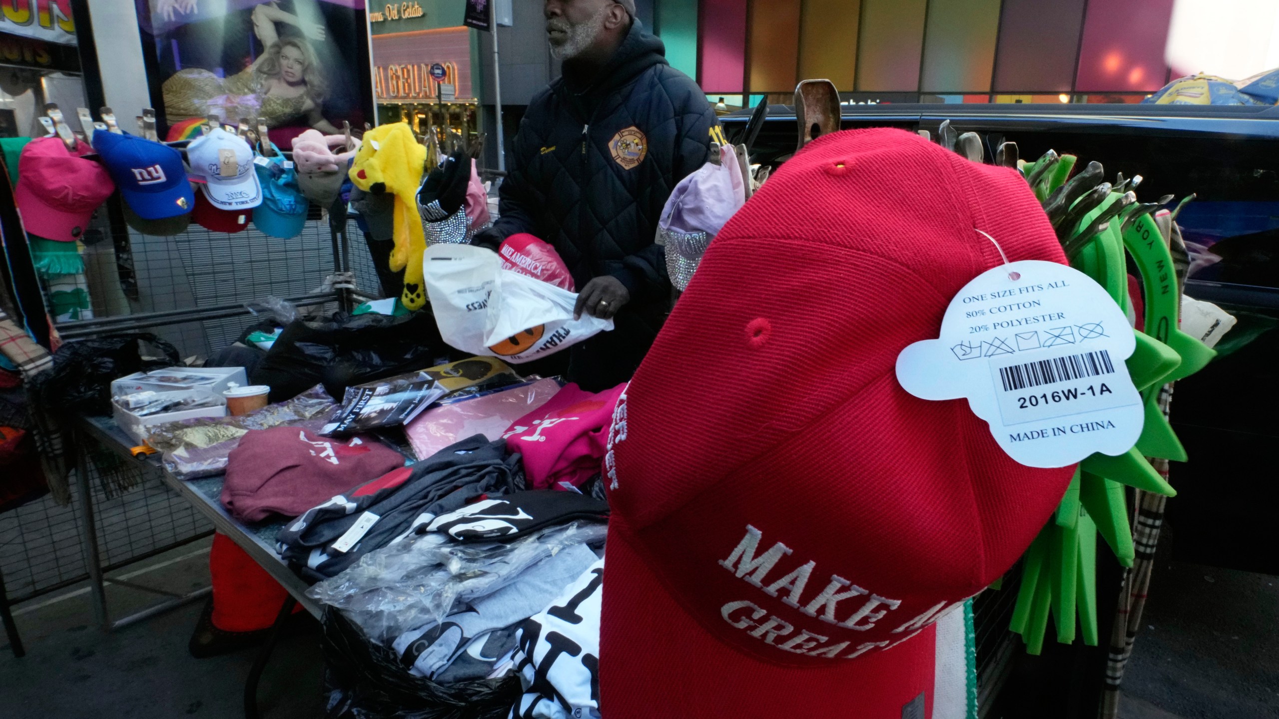 Souvenir apparel vendor Duane Jackson completes a sale of "Make America Great Again" caps, that are made in China, at his location in New York's Times Square, Tuesday, April 1, 2025. (AP Photo/Richard Drew)