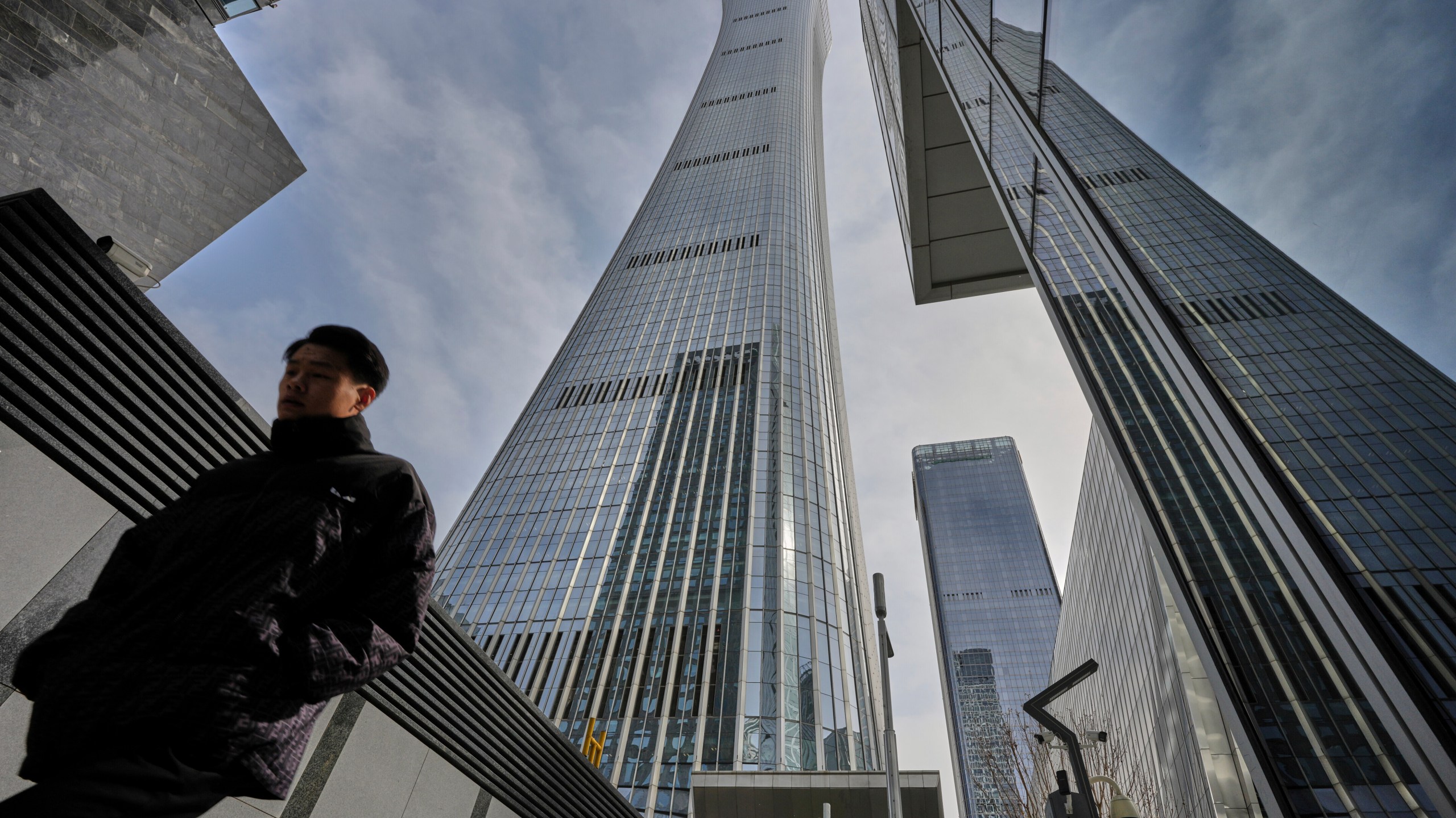 A man walks by high rise office buildings in the central business district, in Beijing, Tuesday, April 8, 2025. (AP Photo/Andy Wong)