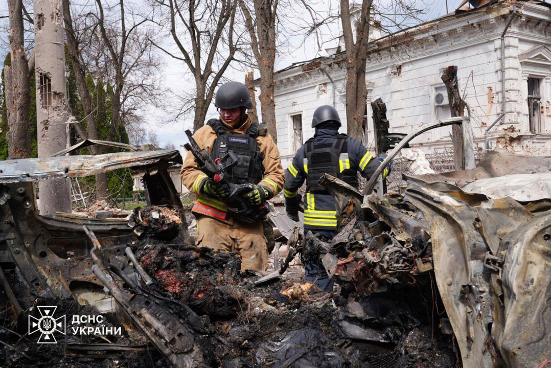 In this photo provided by the Ukrainian Emergency Service, firefighters inspects a burnt car with victims inside following Russia's missile attack that killed at least 24 civilians in Sumy, Ukraine, Sunday, April 13, 2025. (Ukrainian Emergency Service via AP)