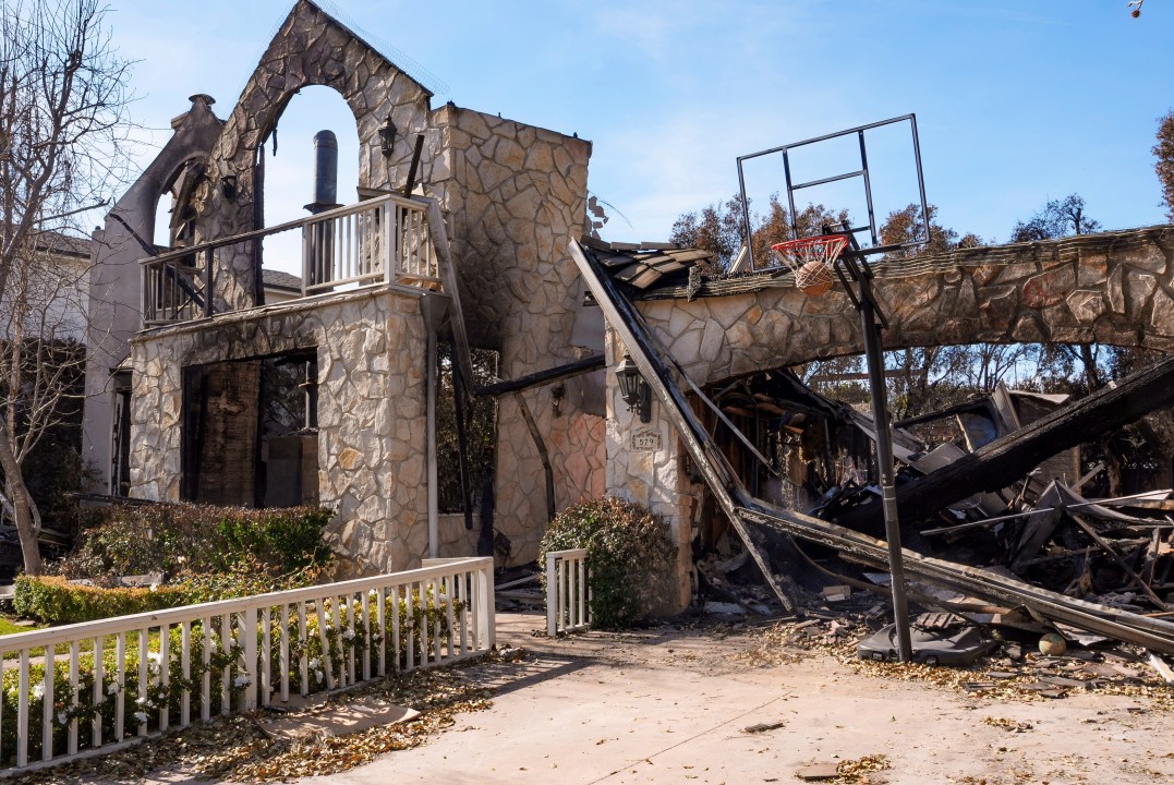 A basketball is stuck in the net outside of a destroyed home
