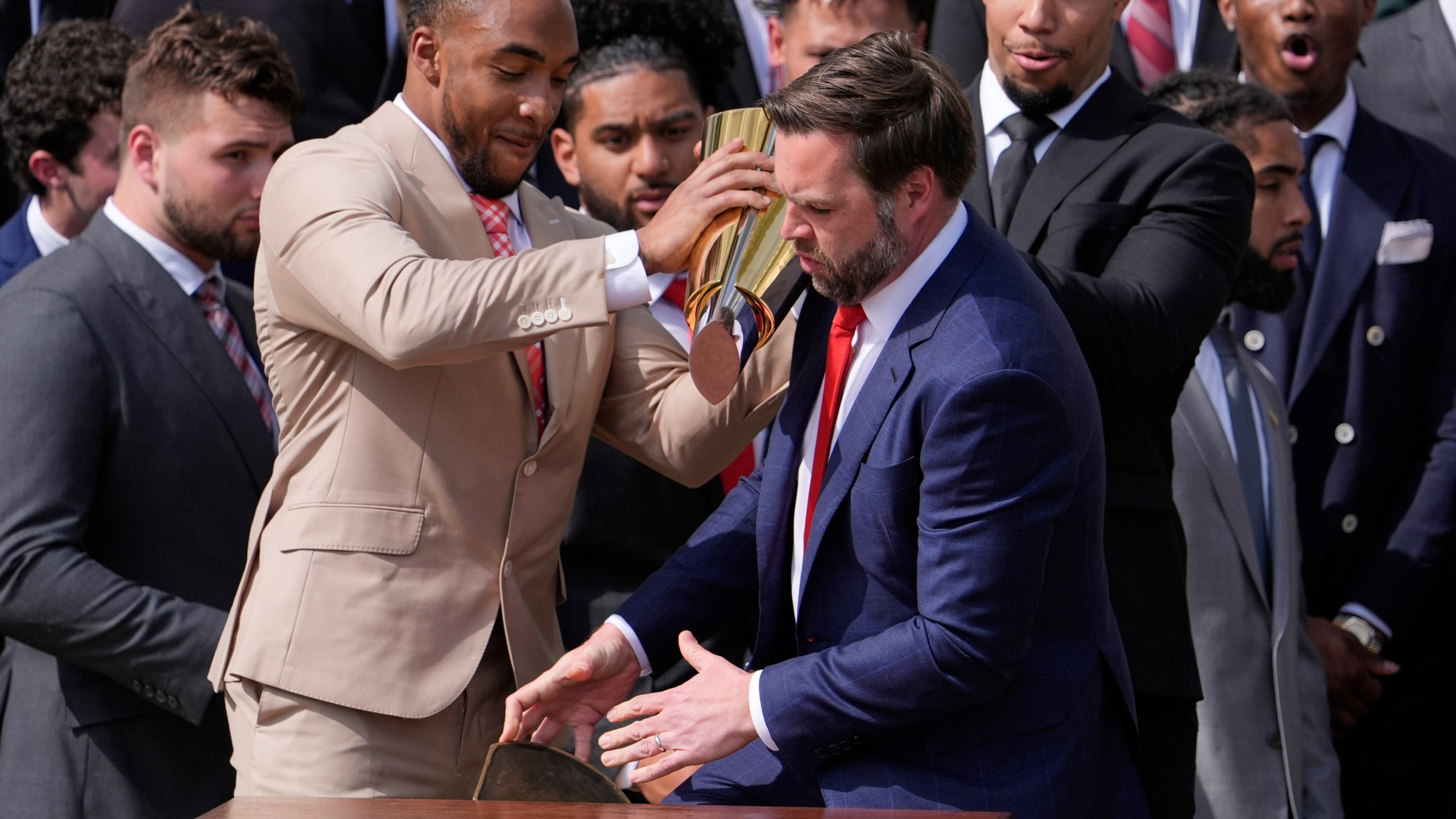 Ohio State University football player TreVeyon Henderson, left, holds the top of the team's championship trophy as Vice President JD Vance reaches to catch it's base after it fell off, as President Donald Trump welcomes the 2025 College Football National Champions during an event on the South Lawn of the White House, Monday, April 14, 2025, in Washington. (AP Photo/Manuel Balce Ceneta)