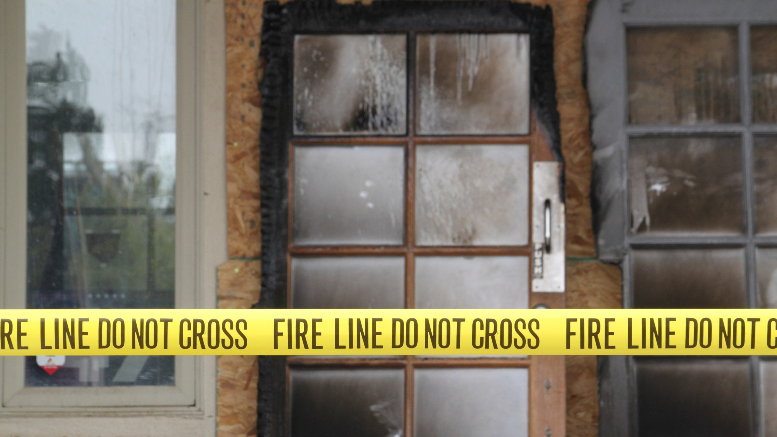 The charred doors that used to make up the entrance to the Republican Party of New Mexico headquarters are propped up behind yellow caution tape in Albuquerque, New Mexico, Monday, March 31, 2025. (AP Photo/Susan Montoya Bryan)
