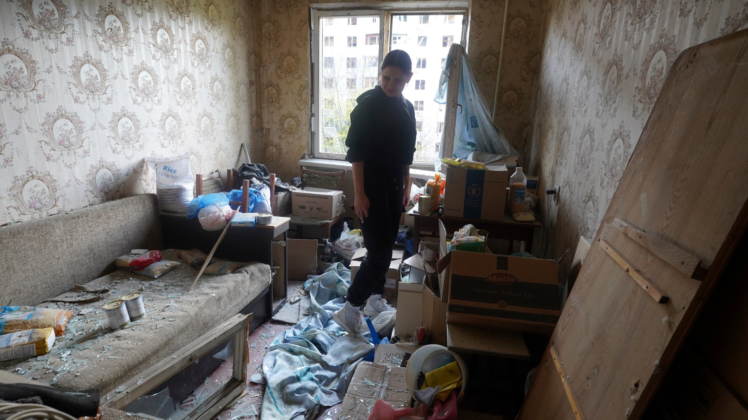 A woman stands inside her apartment damaged by a Russian strike in Kharkiv, Ukraine, Friday April 18, 2025. (AP Photo/Andrii Marienko)
