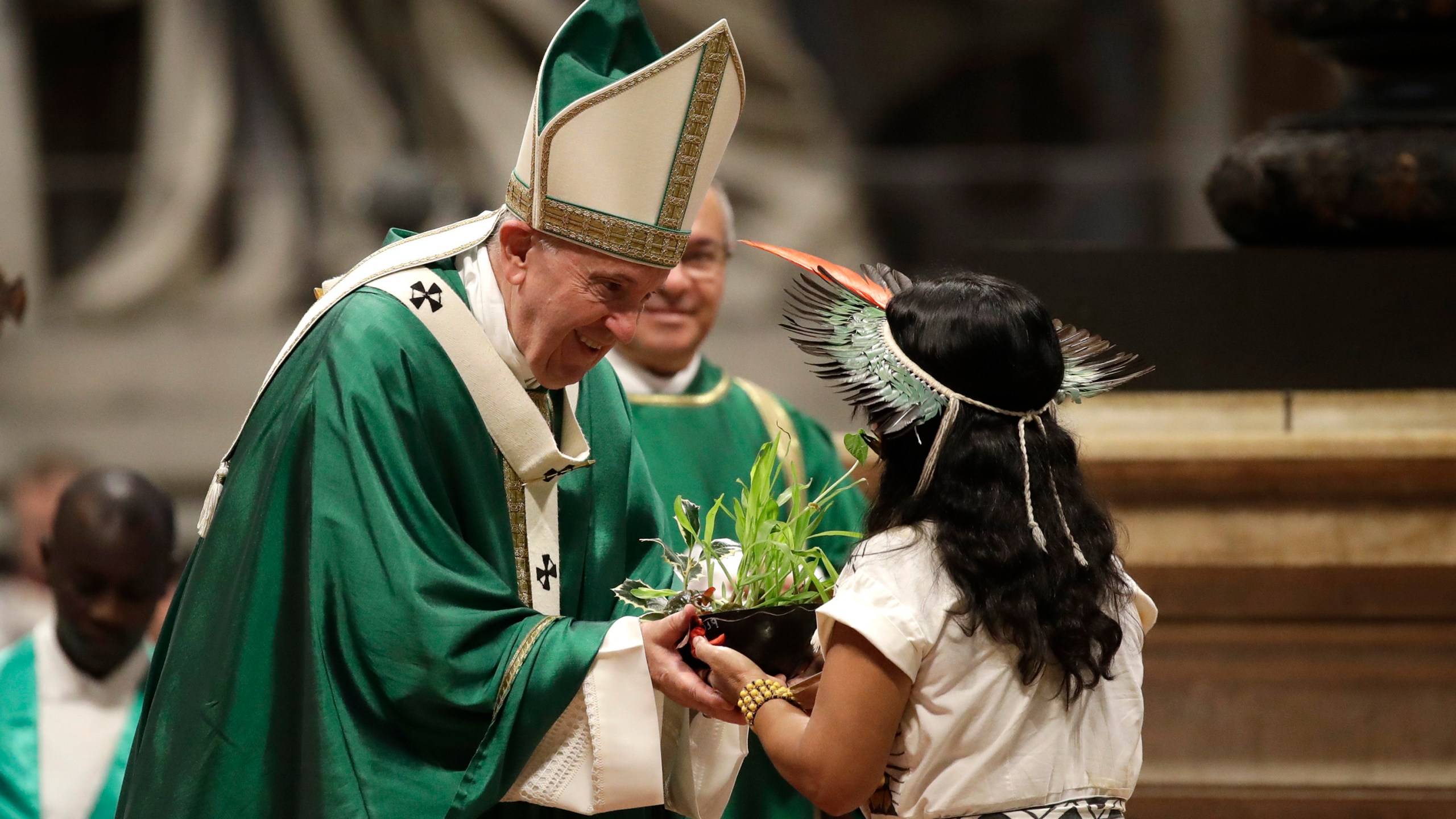 FILE - An Amazzonian indigenous girl gives Pope Francis a plant during the offertory of a Mass for the closing of Amazon synod in St. Peter's Basilica at the Vatican, Sunday, Oct. 27, 2019. (AP Photo/Alessandra Tarantino, file)