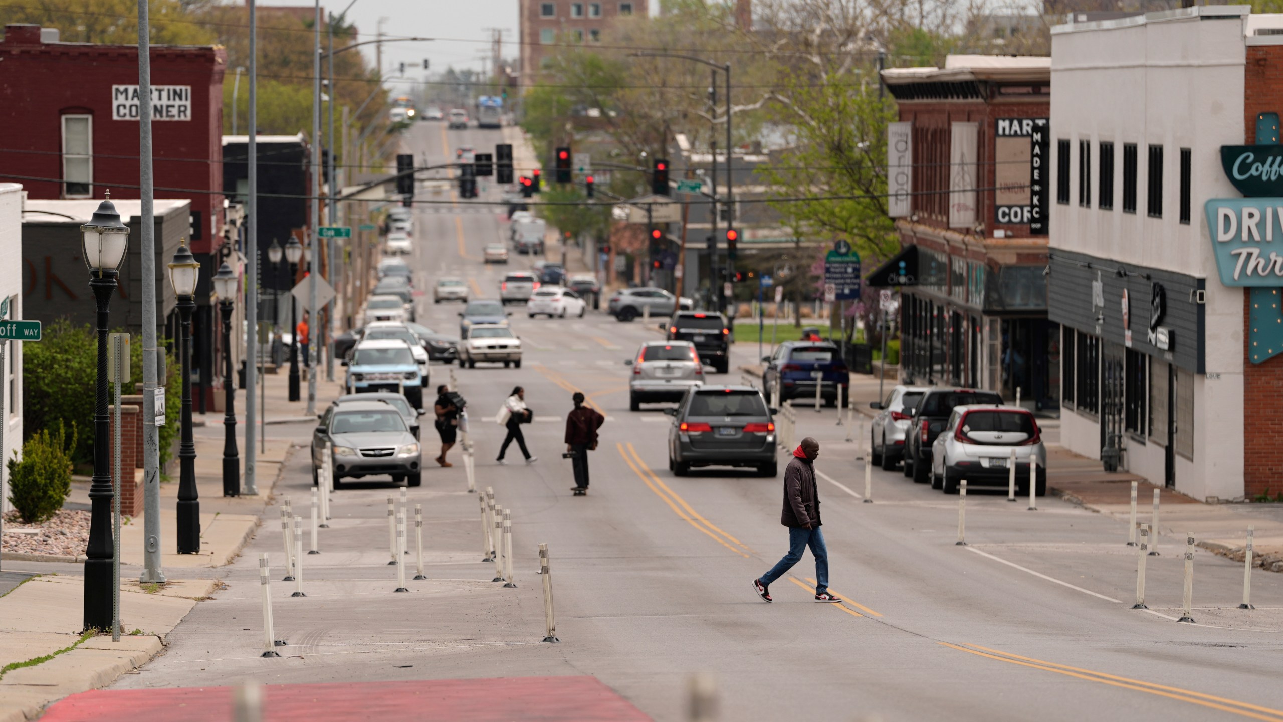 People cross 31st Street in Kansas City, Mo., where the city implemented a "road diet" reducing the street from four lanes to two in an effort to reduce speeding and accidents, Thursday, April 17, 2025. (AP Photo/Charlie Riedel)
