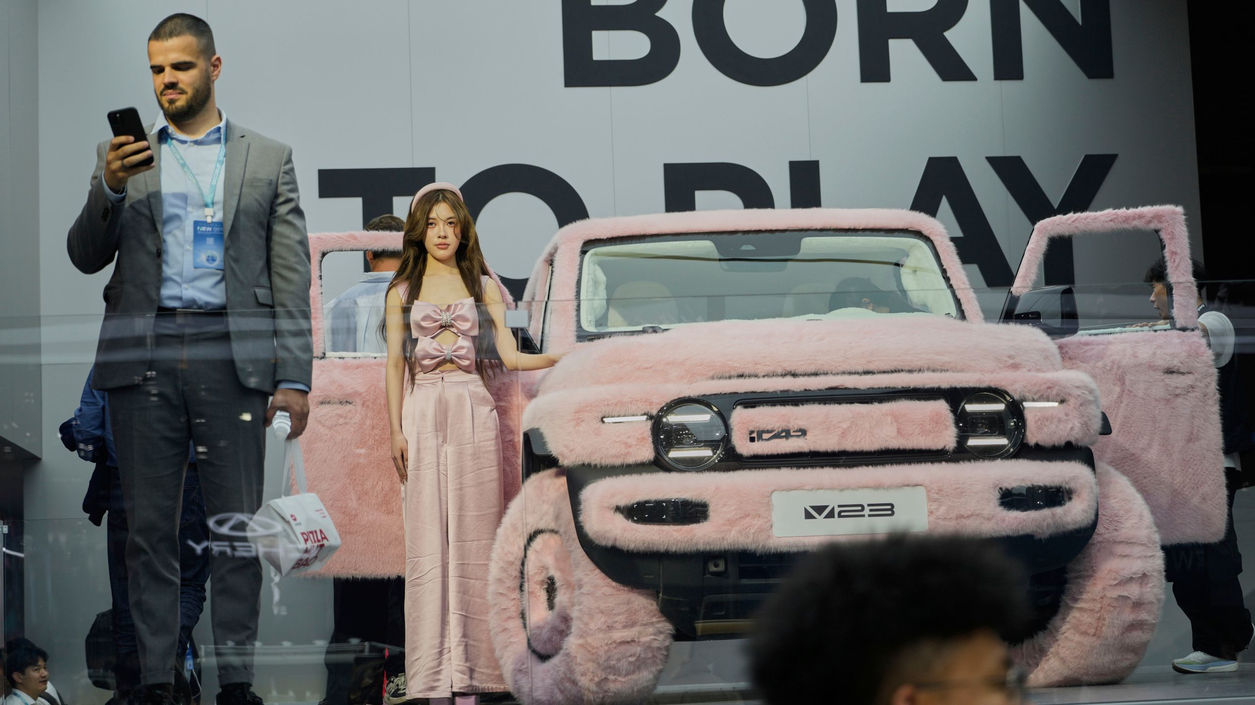 A woman stands next to a iCar 23 decked out with pink fur at the Shanghai auto show on Wednesday, April 23, 2025. (AP Photo/Ng Han Guan)