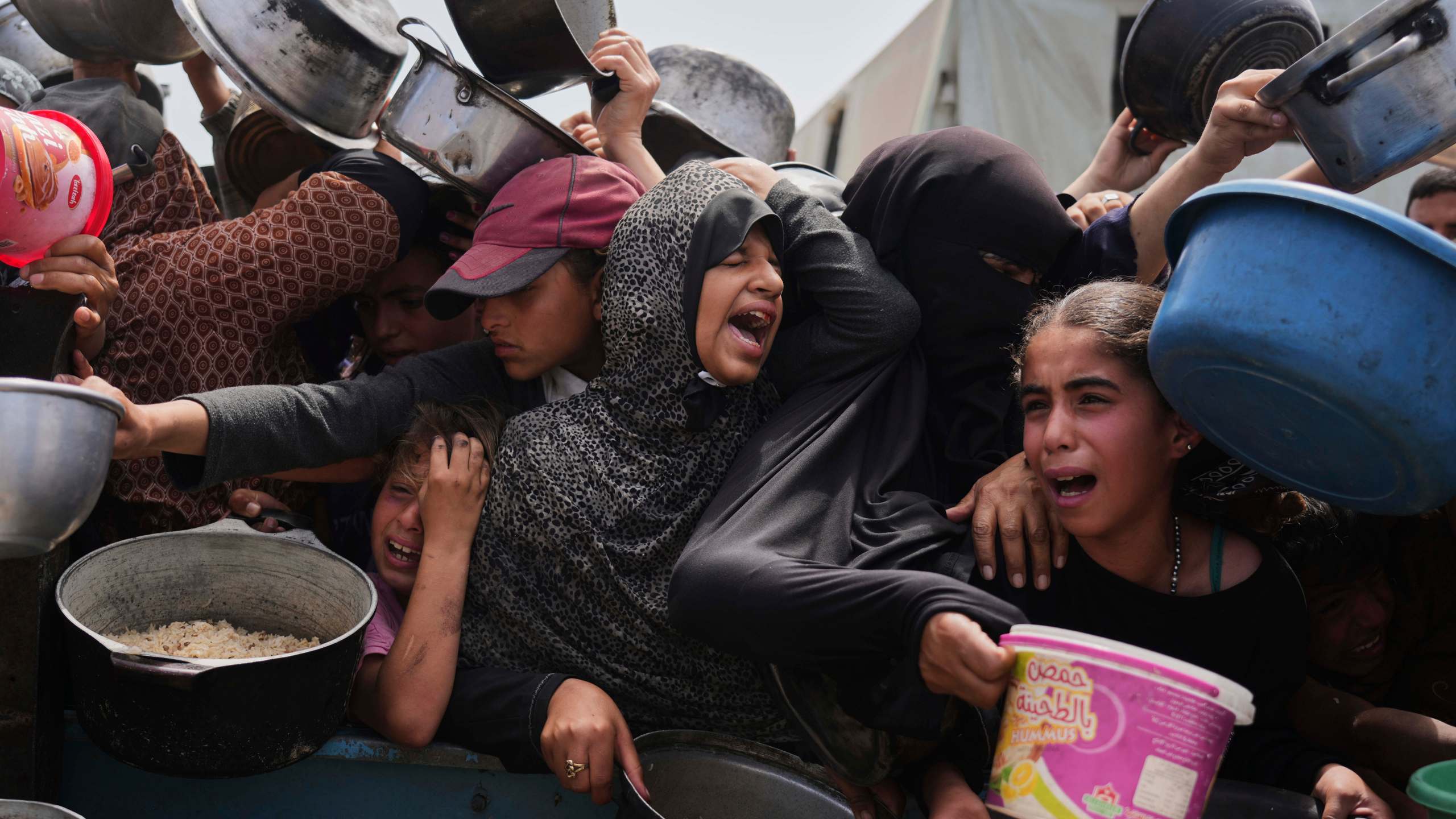 Palestinian children receive donated food at a distribution center in Khan Younis, Gaza Strip, Monday, April 21, 2025. (AP Photo/Abdel Kareem Hana)