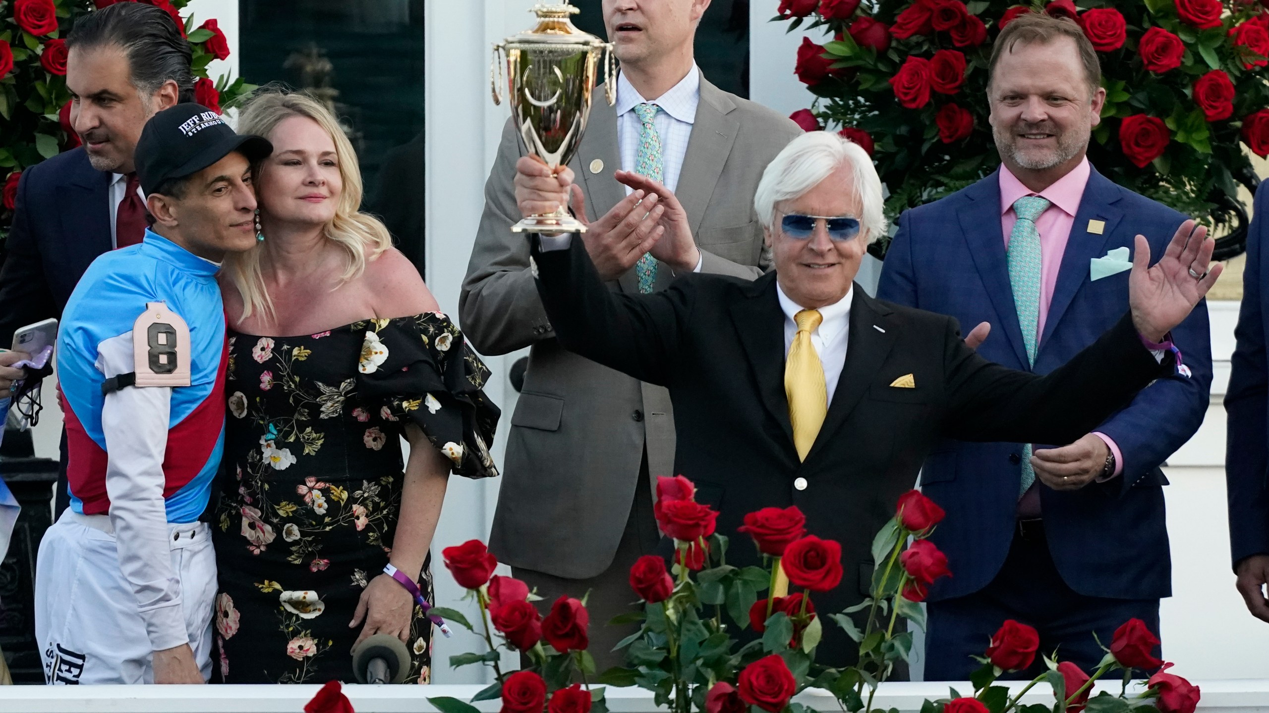 FILE - Jockey John Velazquez, front left, stands with Jill Baffert as they watch as Jill's husband, trainer Bob Baffert, holds up the winner's trophy after Medina Spirit won the 147th running of the Kentucky Derby at Churchill Downs in Louisville, Ky. (AP Photo/Jeff Roberson, File)