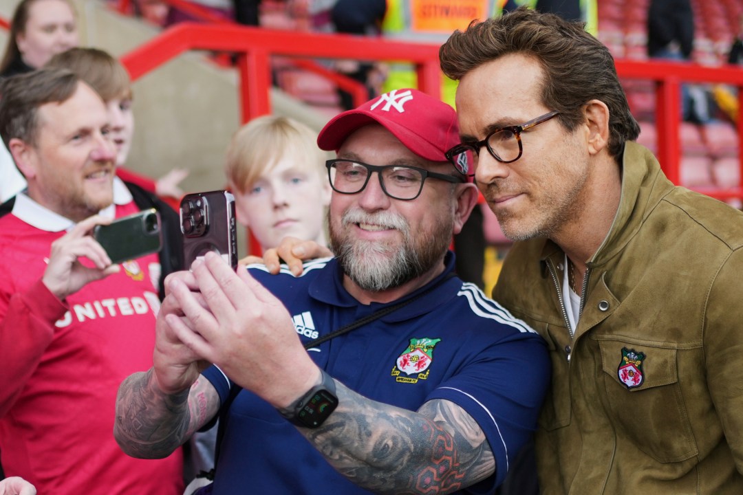 Wrexham co-owners Ryan Reynolds, right, poses with fans before the English League One soccer match between Wrexham and Charlton Athletic at the Racecourse ground in Wrexham, Wales, Saturday, April 26, 2025. (AP Photo/Jon Super)