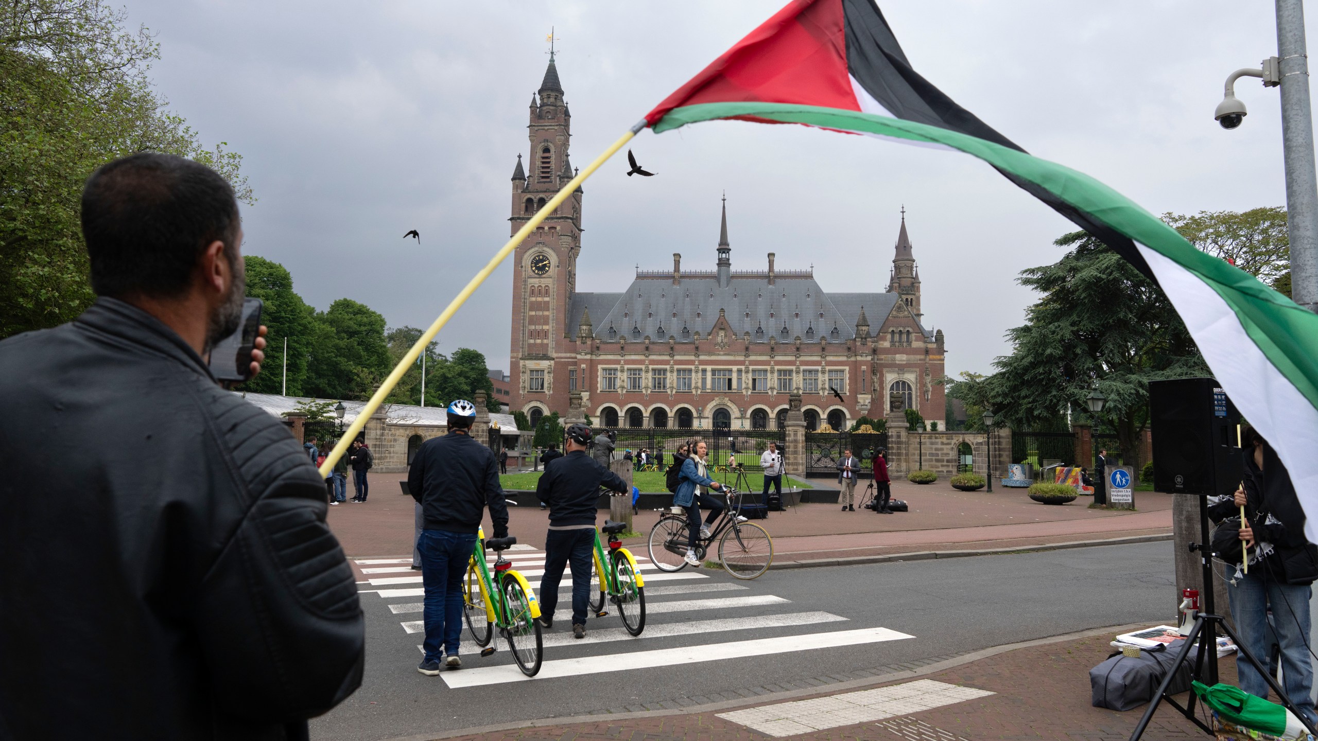 FILE - A lone demonstrator waves the Palestinian flag outside the Peace Palace, rear, housing the International Court of Justice, or World Court, in The Hague, Netherlands, on May 24, 2024. (AP Photo/Peter Dejong, File)