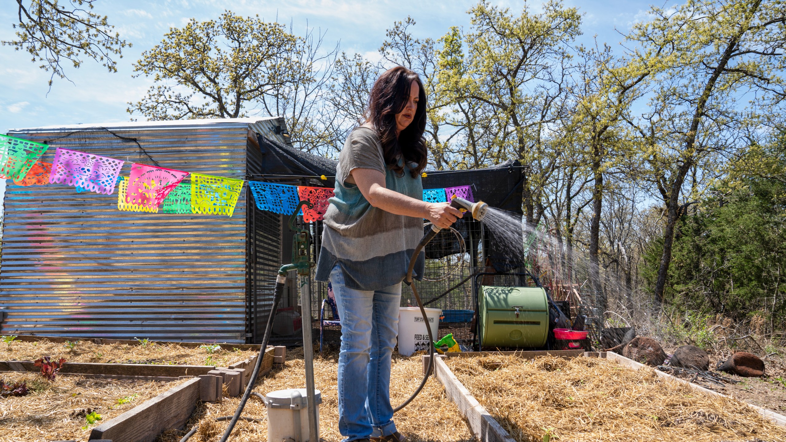 Erika Wright, a mother whose two school-age children attend a rural school district in Cleveland County waters her garden at her home in Noble, Okla., on Tuesday, April 15, 2025. (AP Photo/Nick Oxford)
