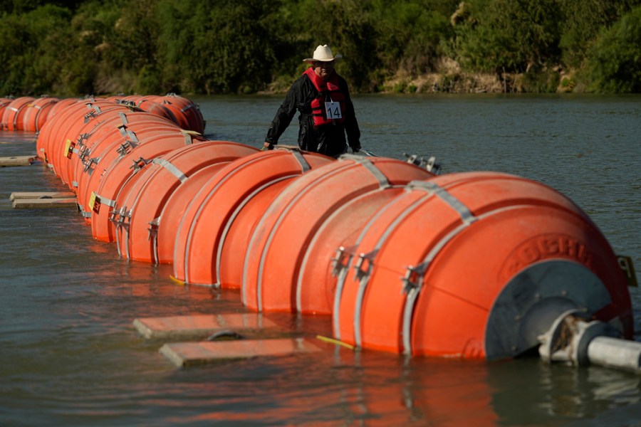 Kayaker looks at buoy border barrier in the Rio Grande River in Texas.