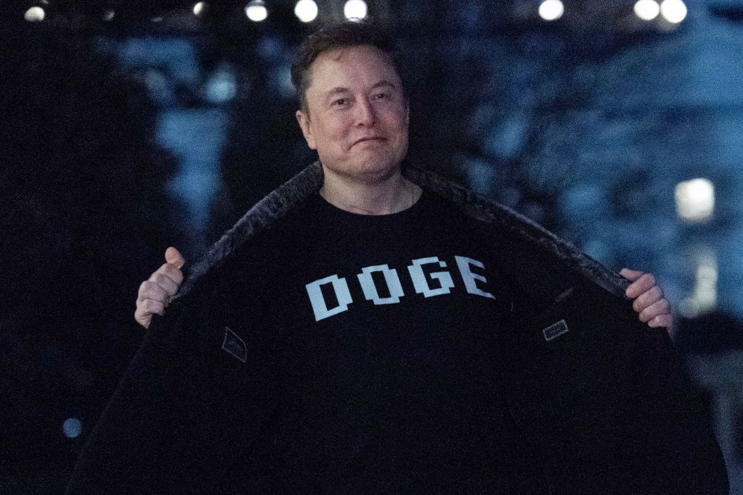 Elon Musk flashes his T-shirt that reads "DOGE"