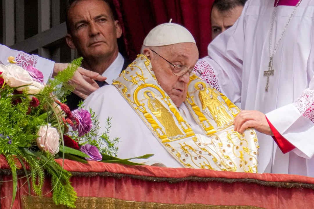 Pope Francis sits on a balcony to give a blessing after Easter Mass.