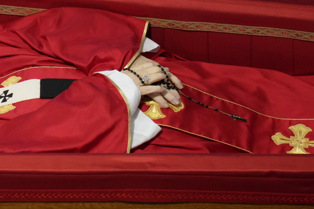 Pope Francis' hands clasping a rosary as his body lies in state