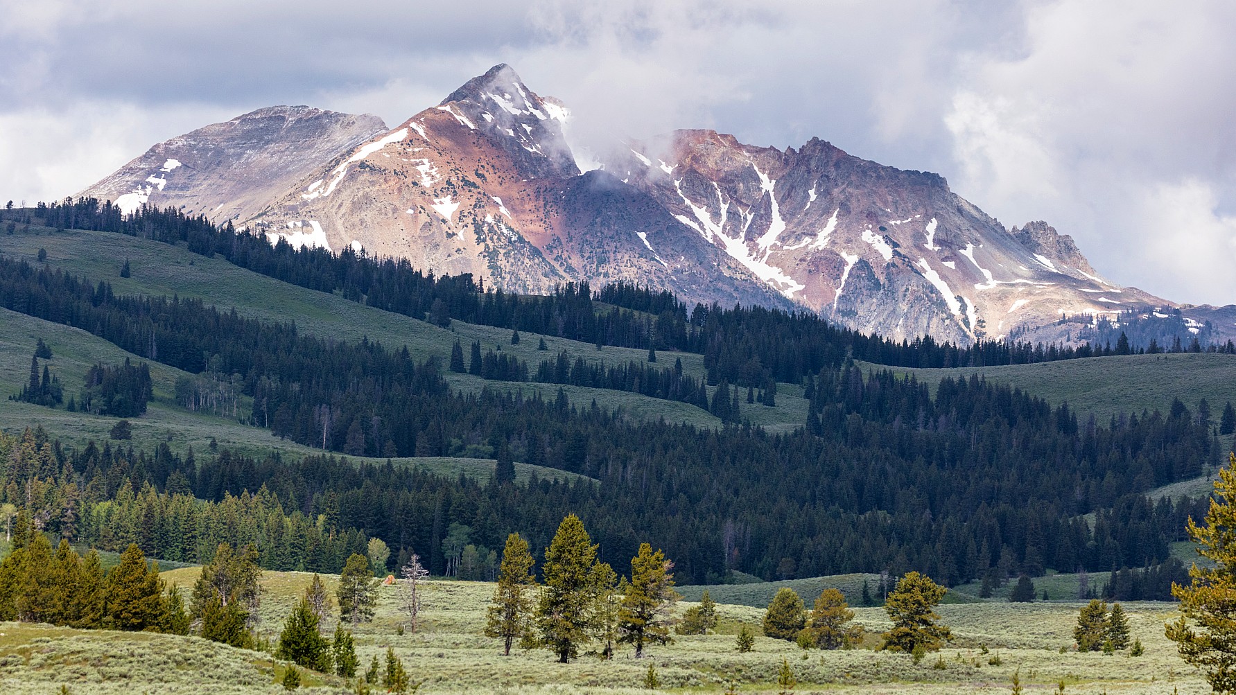 A scenic photo shows clouds rolling over Electric Peak, the tallest peak in the Gallatin Range. Electric Peak is part of Yellowstone National Park.