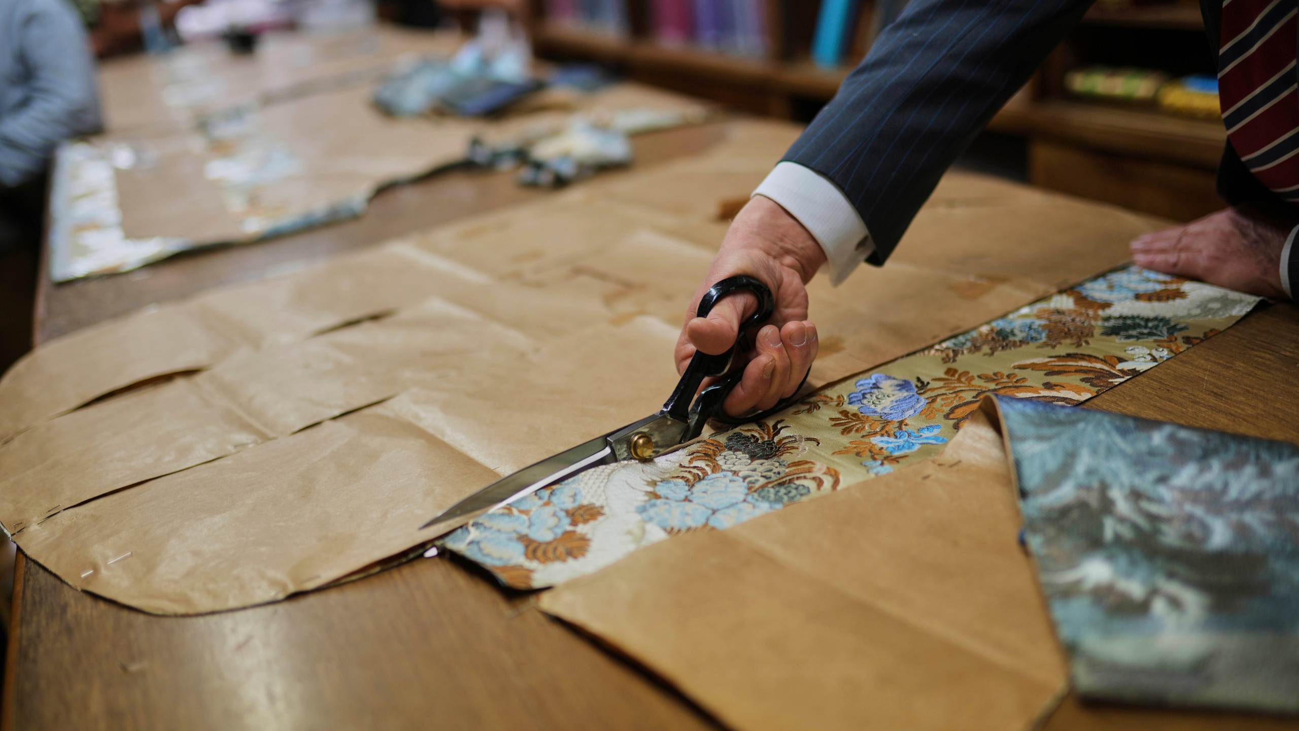 A tailor uses a pattern to cut fabric at the Gammarelli ecclesiastic clothes tailor shop in Rome, Wednesday, April 30, 2025. (AP Photo/Francisco Seco)
