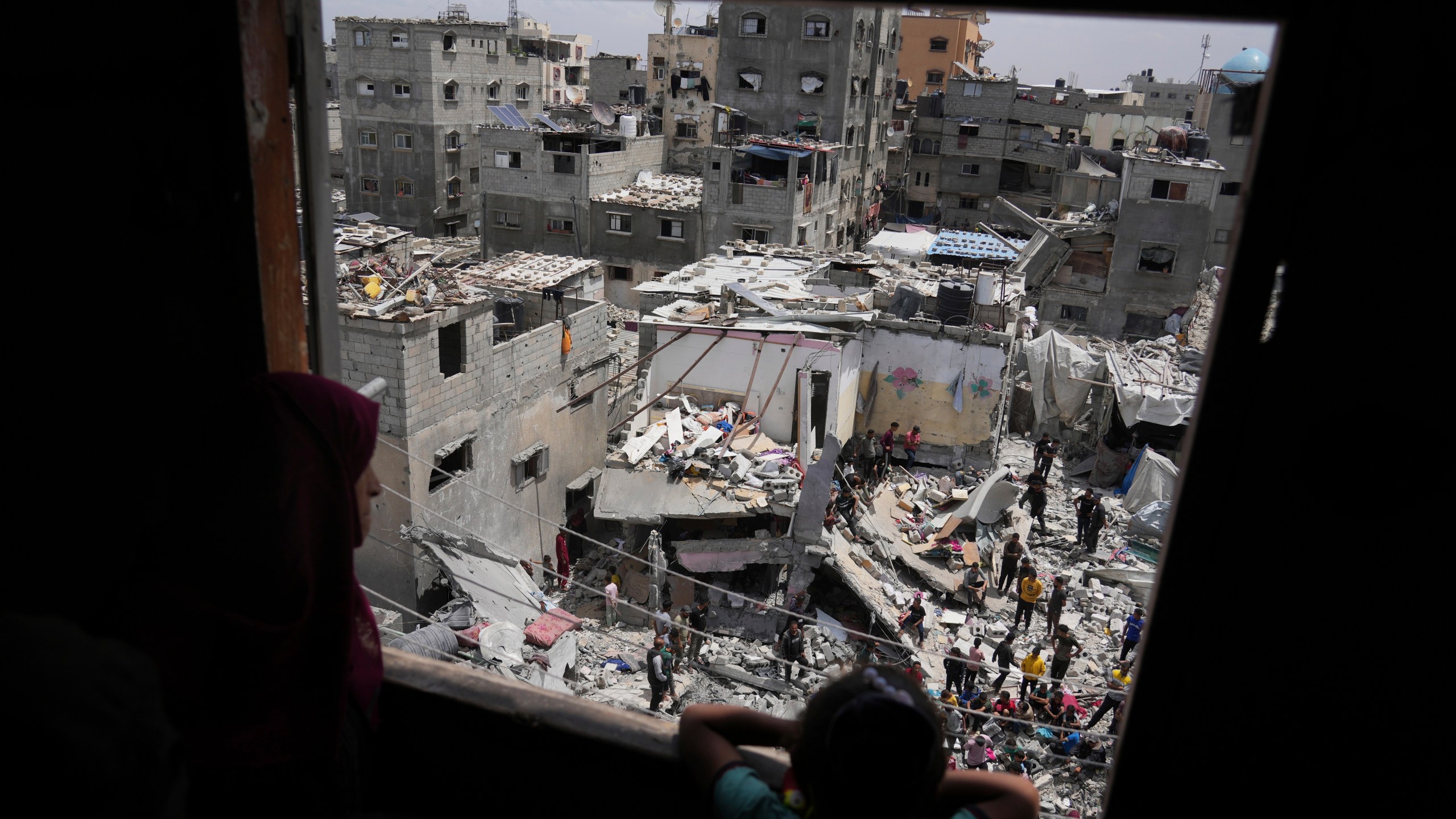 A child and a woman look as Palestinians search the rubble of a house targeted by an Israeli army strike that killed killing at least five members of the Abu Sahloul family in Khan Younis, in the southern Gaza Strip, Thursday, May 1, 2025. (AP Photo/Abdel Kareem Hana)