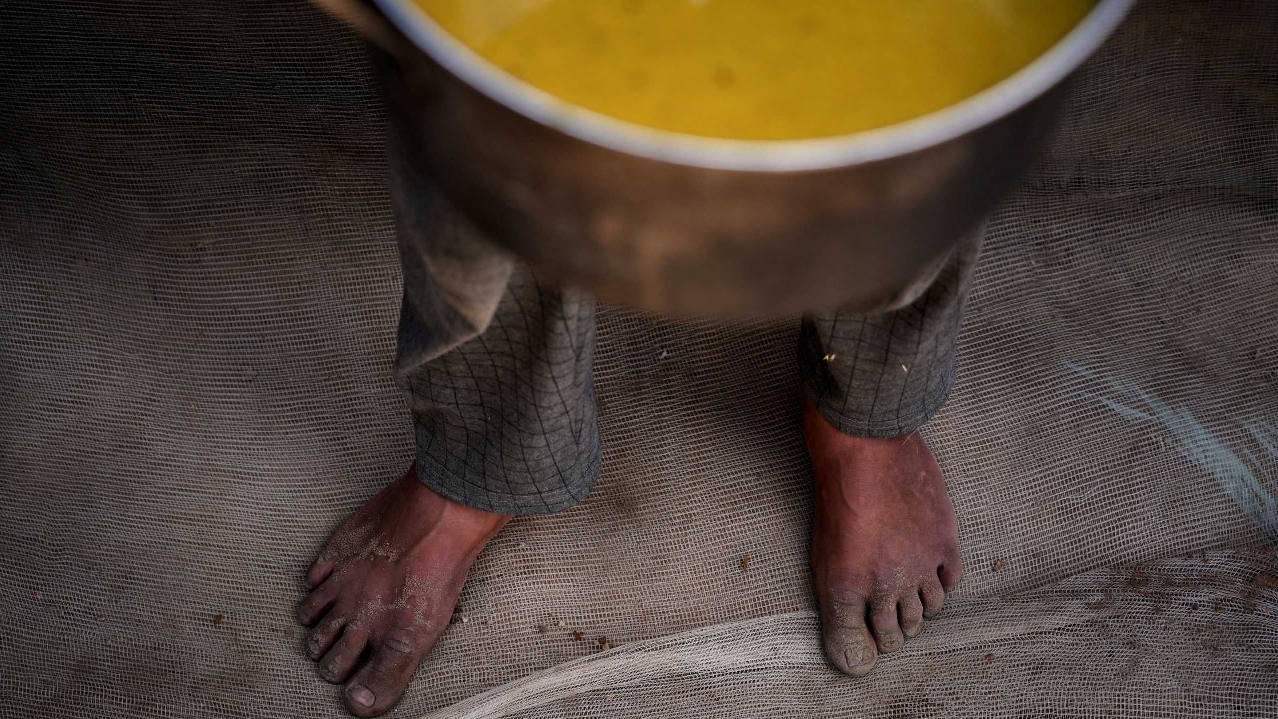 A Palestinian child carries a pot of soup received from a community kitchen in Khan Younis, Gaza Strip, on Saturday, May 3, 2025. (AP Photo/Abdel Kareem Hana)