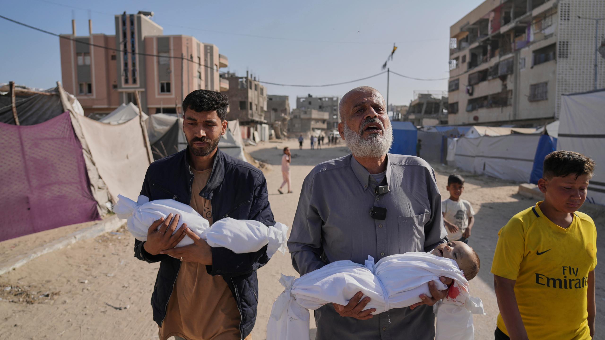 Abdel Rahman Sinwar, left, carries the body of his infant son, Yahia Sinwar, while the child's grandfather carries the body of his one-year-old grandson, Seif Sinwar, both killed in an Israeli army strike in Khan Younis, Gaza Strip, on Saturday, May 3, 2025. (AP Photo/Abdel Kareem Hana)