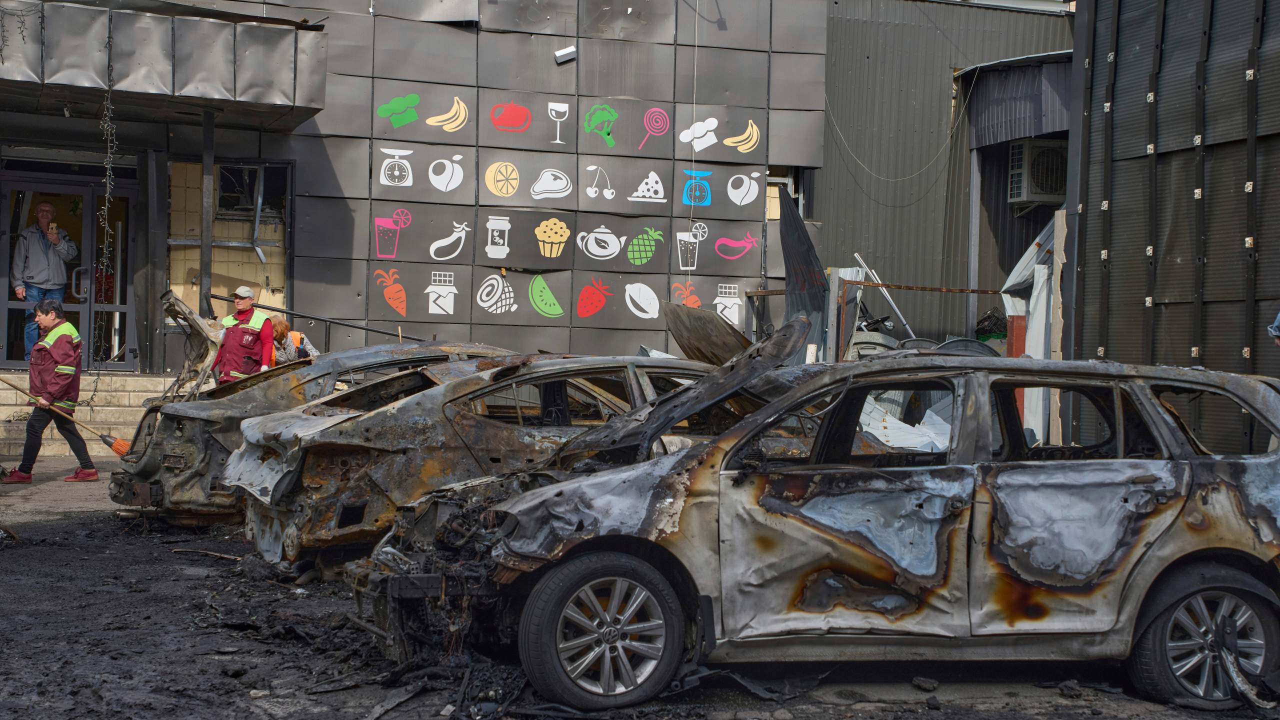 Municipal workers clean up near burnt cars in the residential area following Russia's drone attack in Kyiv, Ukraine, Sunday, May 4, 2025. (AP Photo/Efrem Lukatsky)