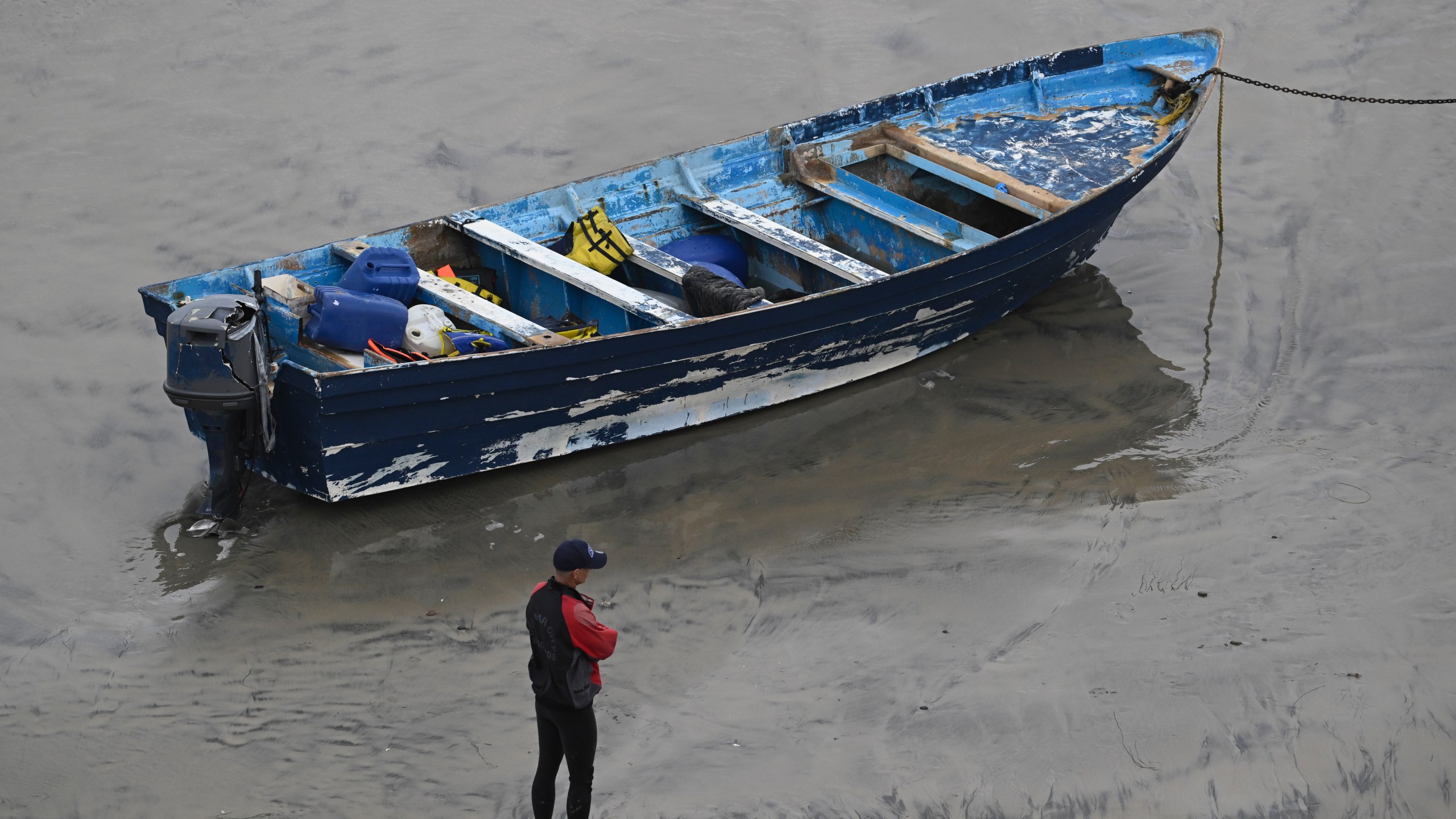 Del Mar lifeguards looks over a capsized boat on the beach Monday, May 5, 2025, in at Torrey Pines State beach in San Diego, Calif. (AP Photo/Denis Poroy)