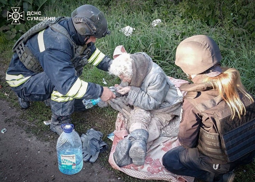 A rescue worker helps an injured elderly woman evacuated from a building