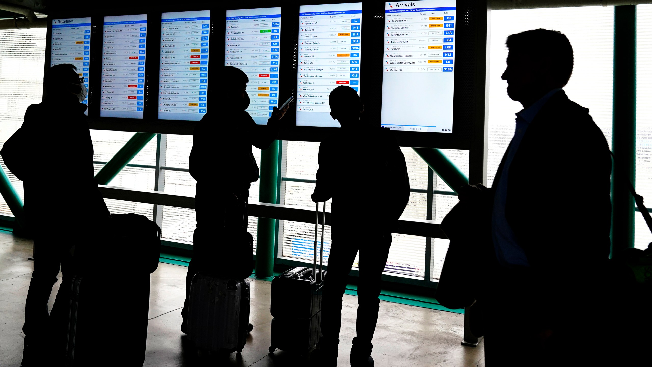 FILE - Travelers check American Airlines flight information screens for their flight status at O'Hare International Airport in Chicago, Wednesday, Feb. 22, 2023. (AP photo/Nam Y. Huh, File)