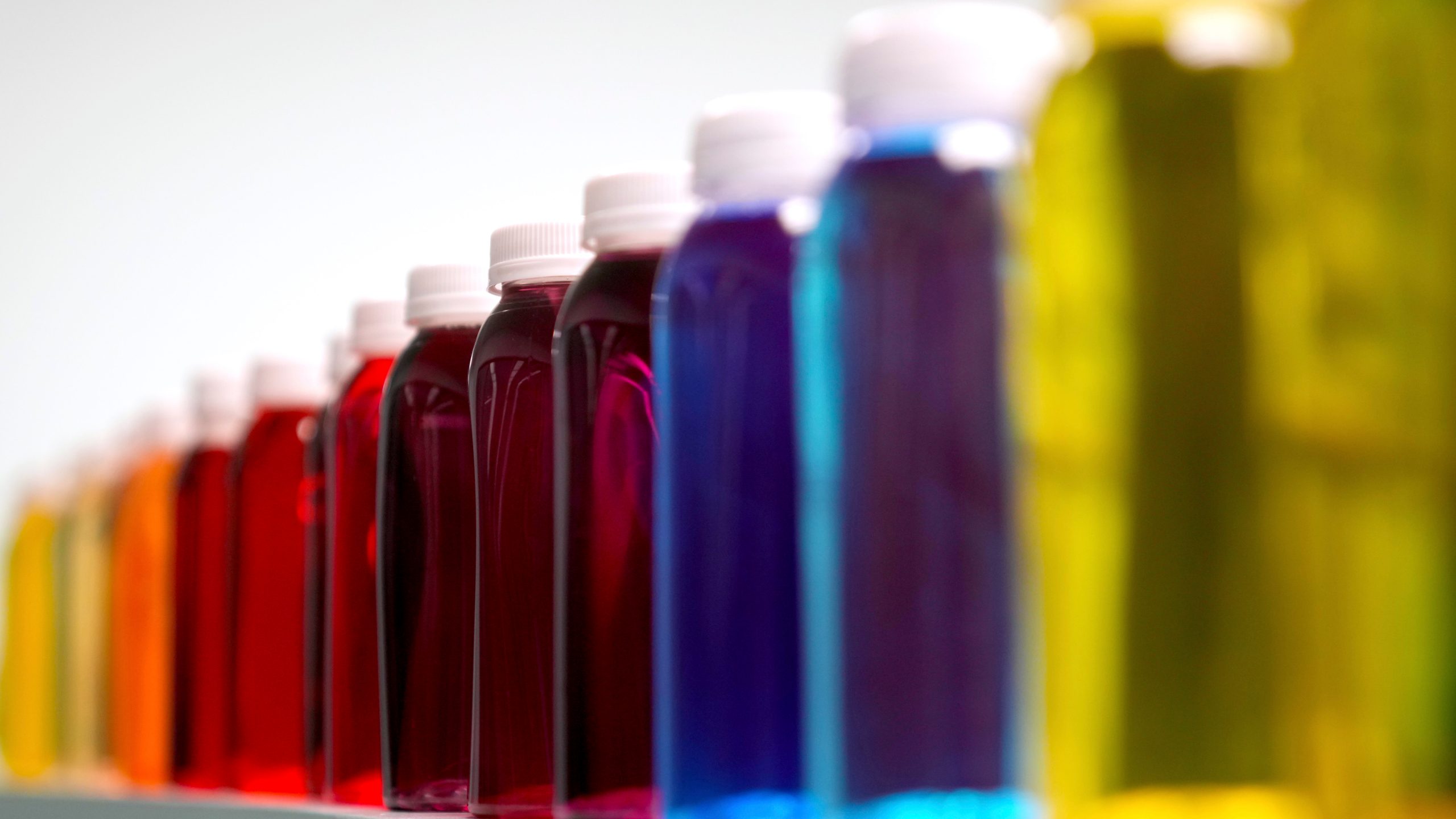 Bottles containing a variety of colored liquids sit on a shelf in a lab