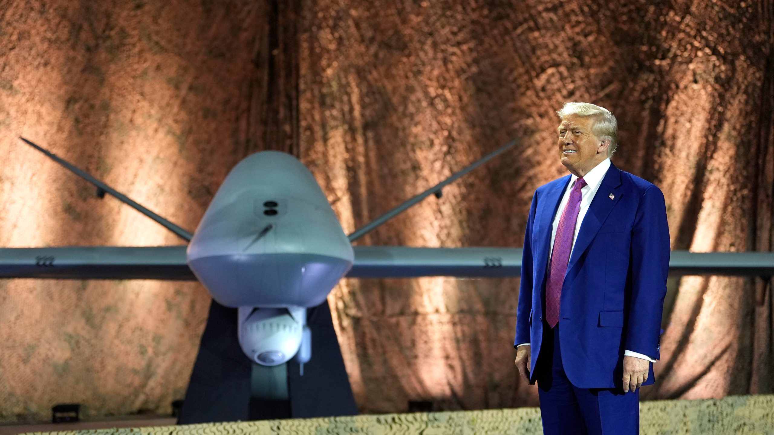 President Donald Trump stands backdropped by an MQ-9 Reaper drone